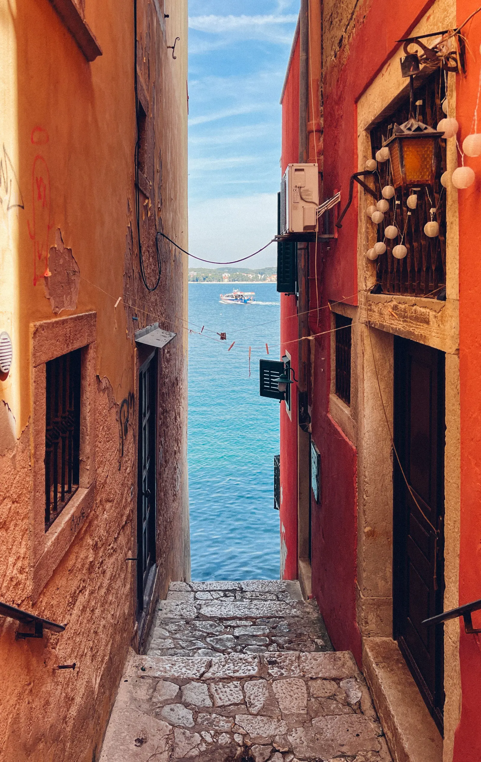 Un vicolo stretto tra muri colorati che scende verso il mare