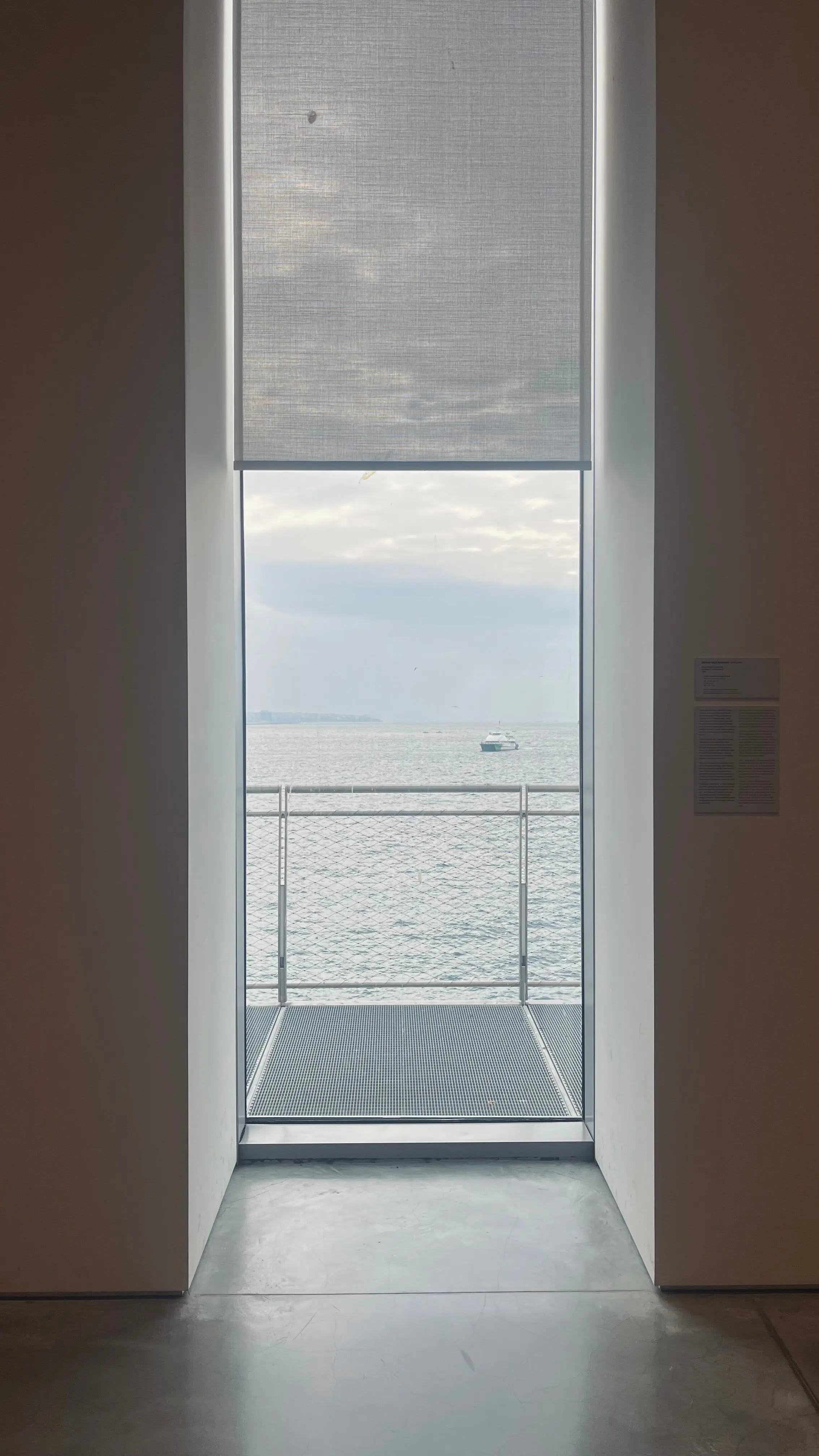 Un corridoio bianco e stretto che finisce su un balcone affacciato sul mare