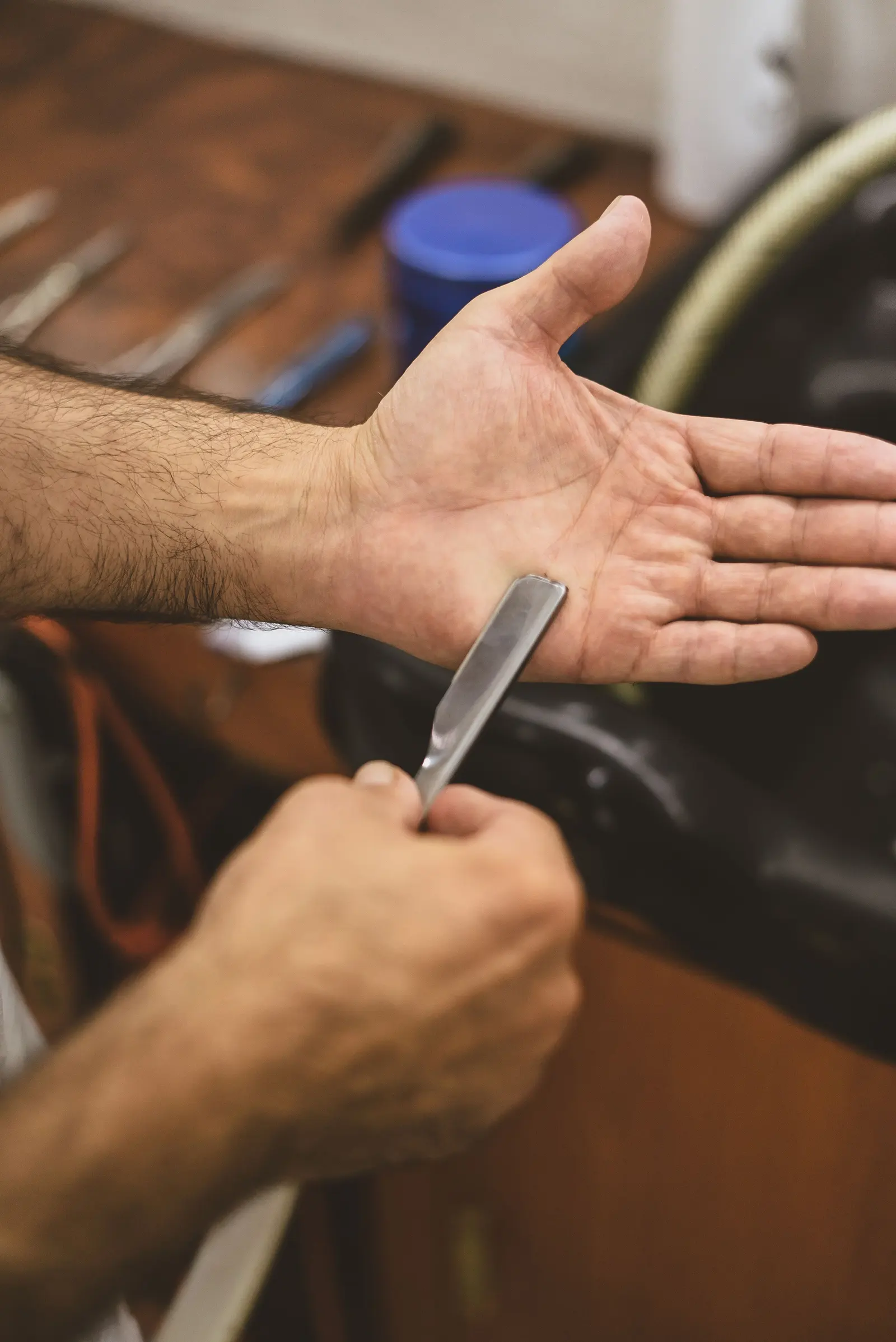 Le mani del barbiere provano il filo del rasoio sul palmo