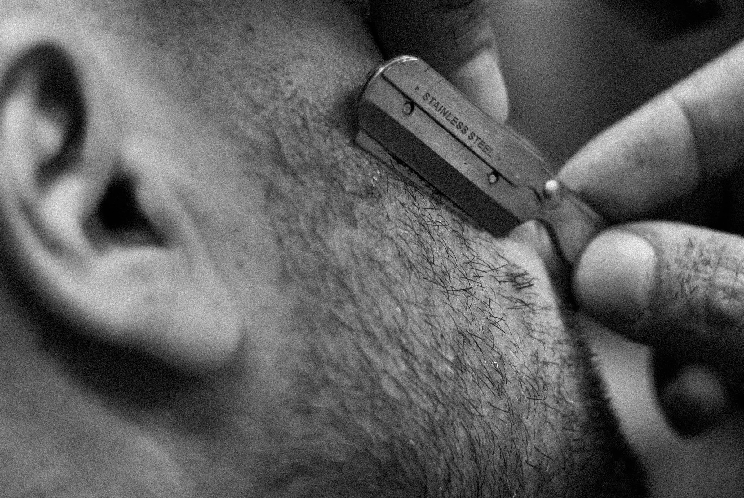 Dettaglio in bianco e nero del rasoio a mano libera che passa sulla guancia