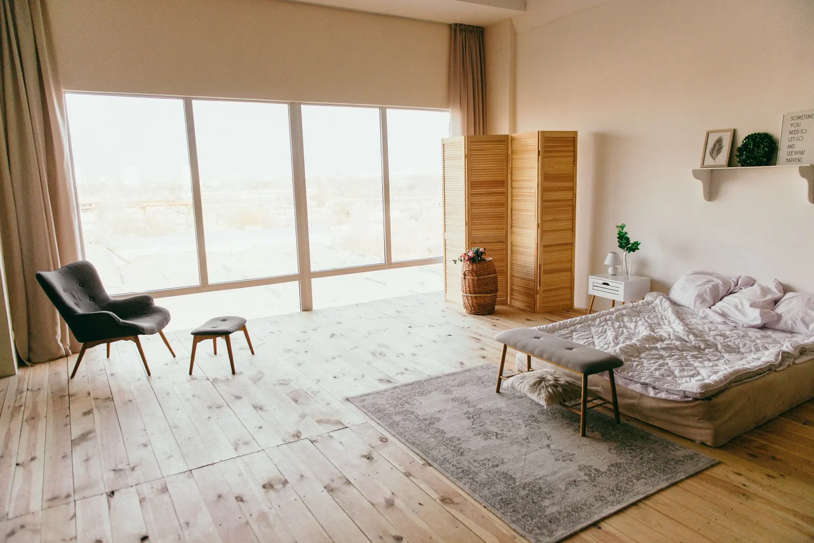 Camera da letto luminosa con grandi vetrate e pavimento in legno