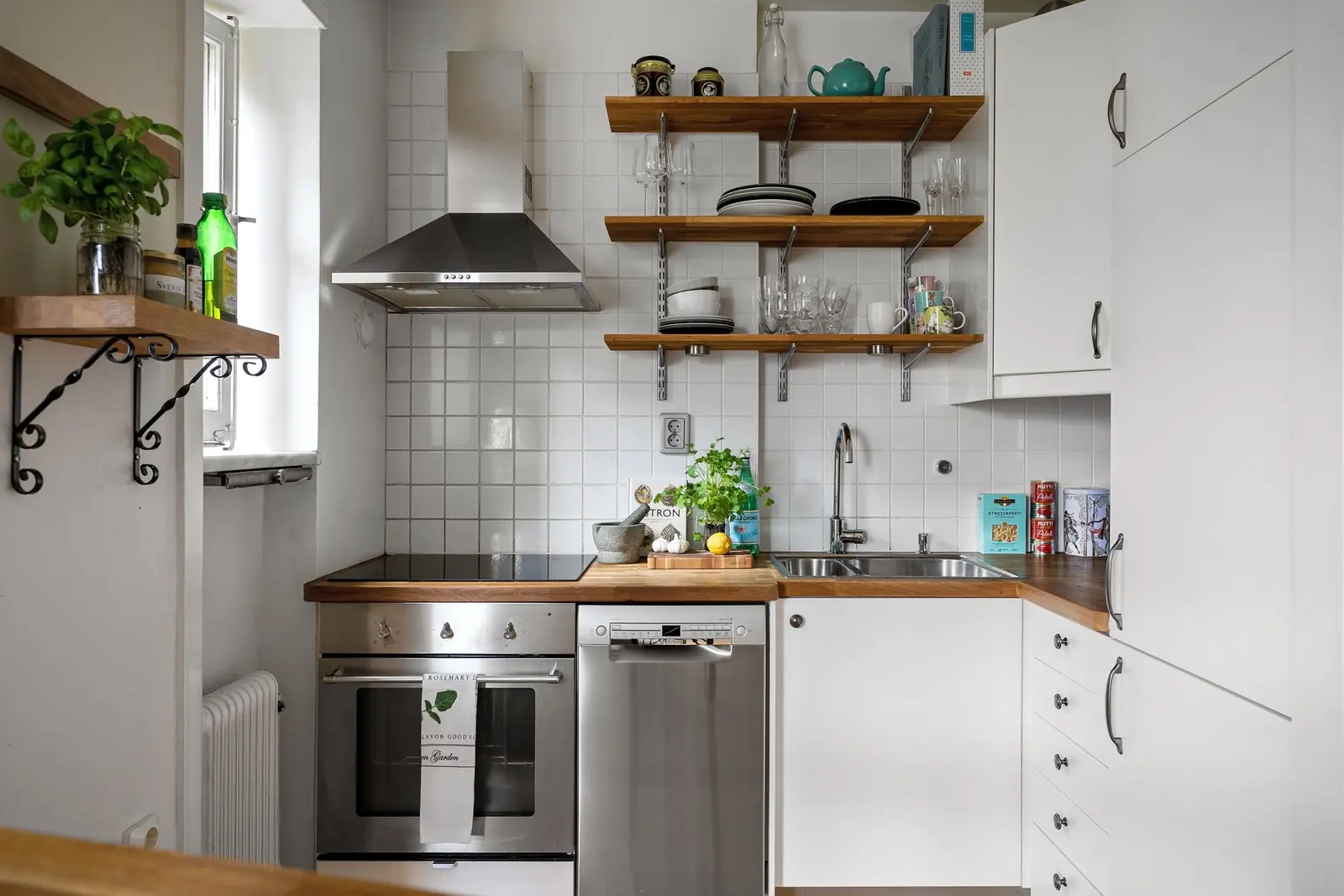Cucina bianca con mensole di legno aperte, forno e finestra