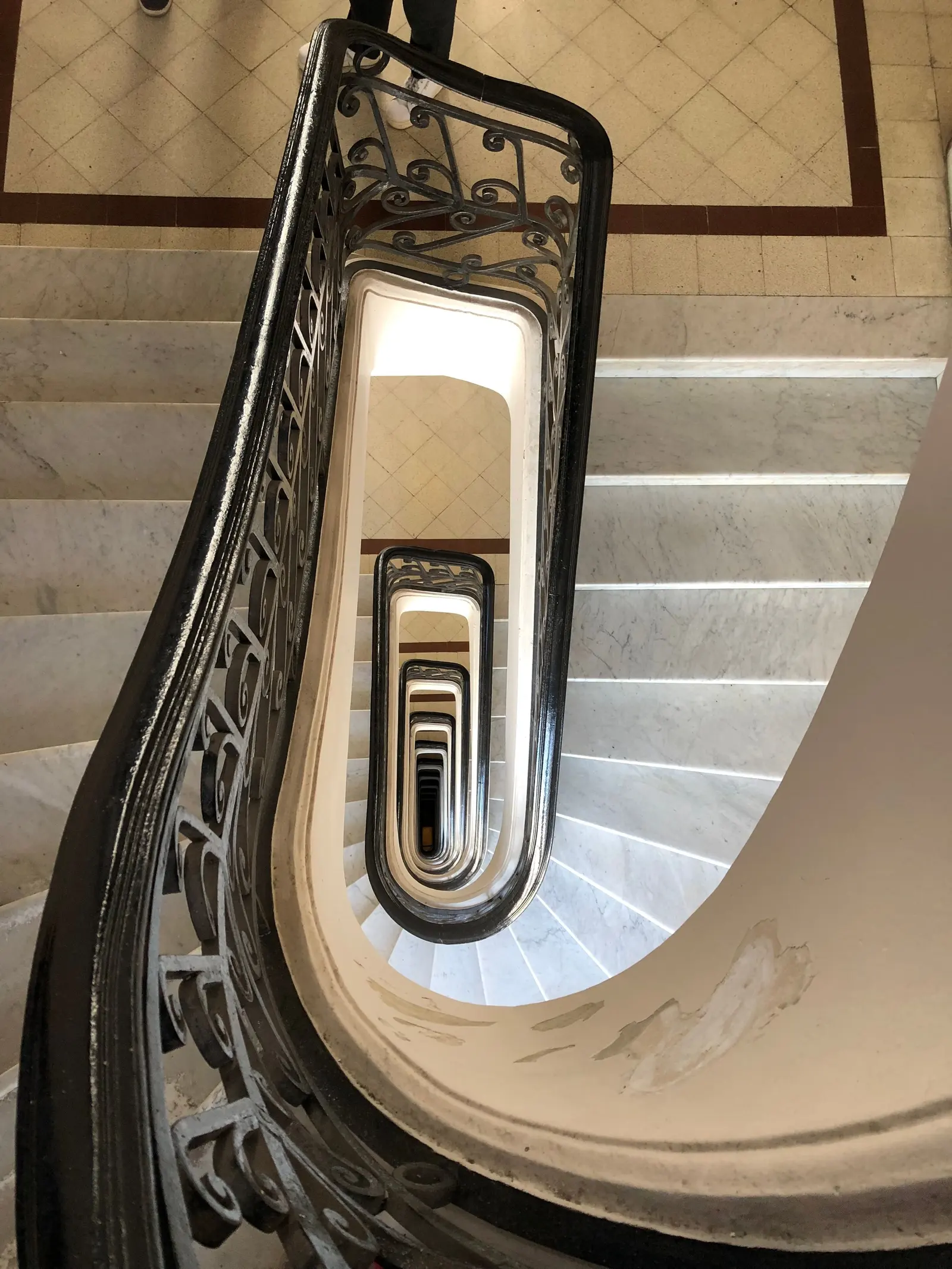 Scala ellittica di un palazzo d'epoca vista dall'alto, con ringhiera in ferro