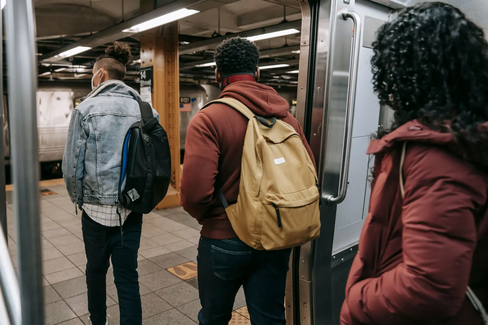 Ragazzi con gli zaini di spalle che salgono su un treno della metropolitana