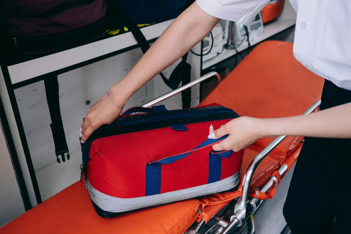 Due mani appoggiano una borsa sanitaria rossa su una barella arancione, dentro un mezzo