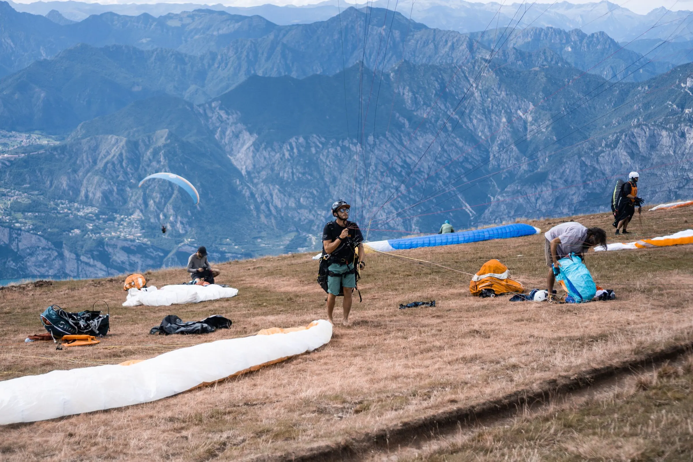 Il prato del decollo in quota con le vele stese a terra e le montagne sopra il lago