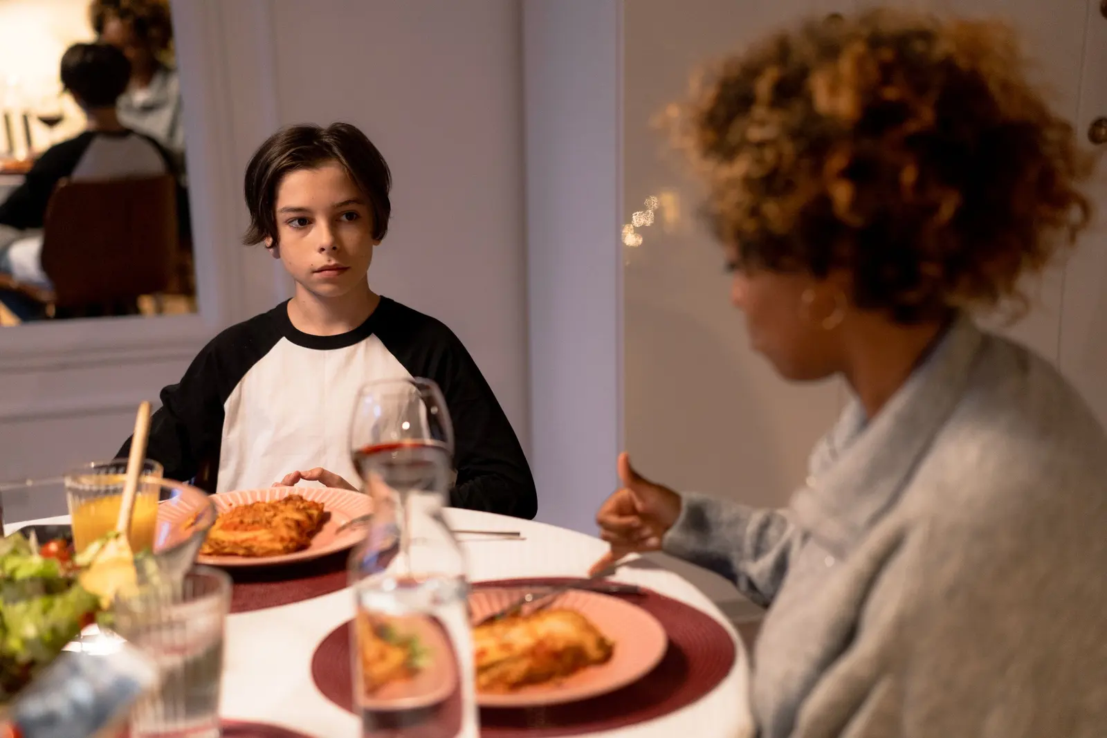 Un ragazzo a cena con la famiglia che lo ospita, piatti di lasagna sulla tavola
