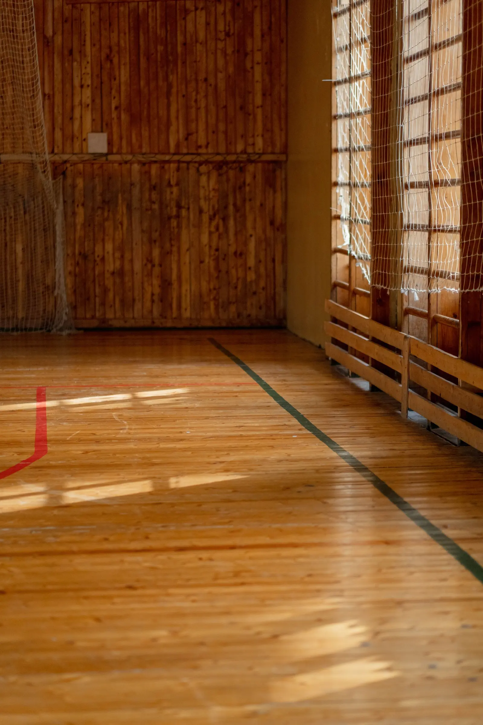 Palestra scolastica con il pavimento in legno, le spalliere al muro e le grate alle finestre