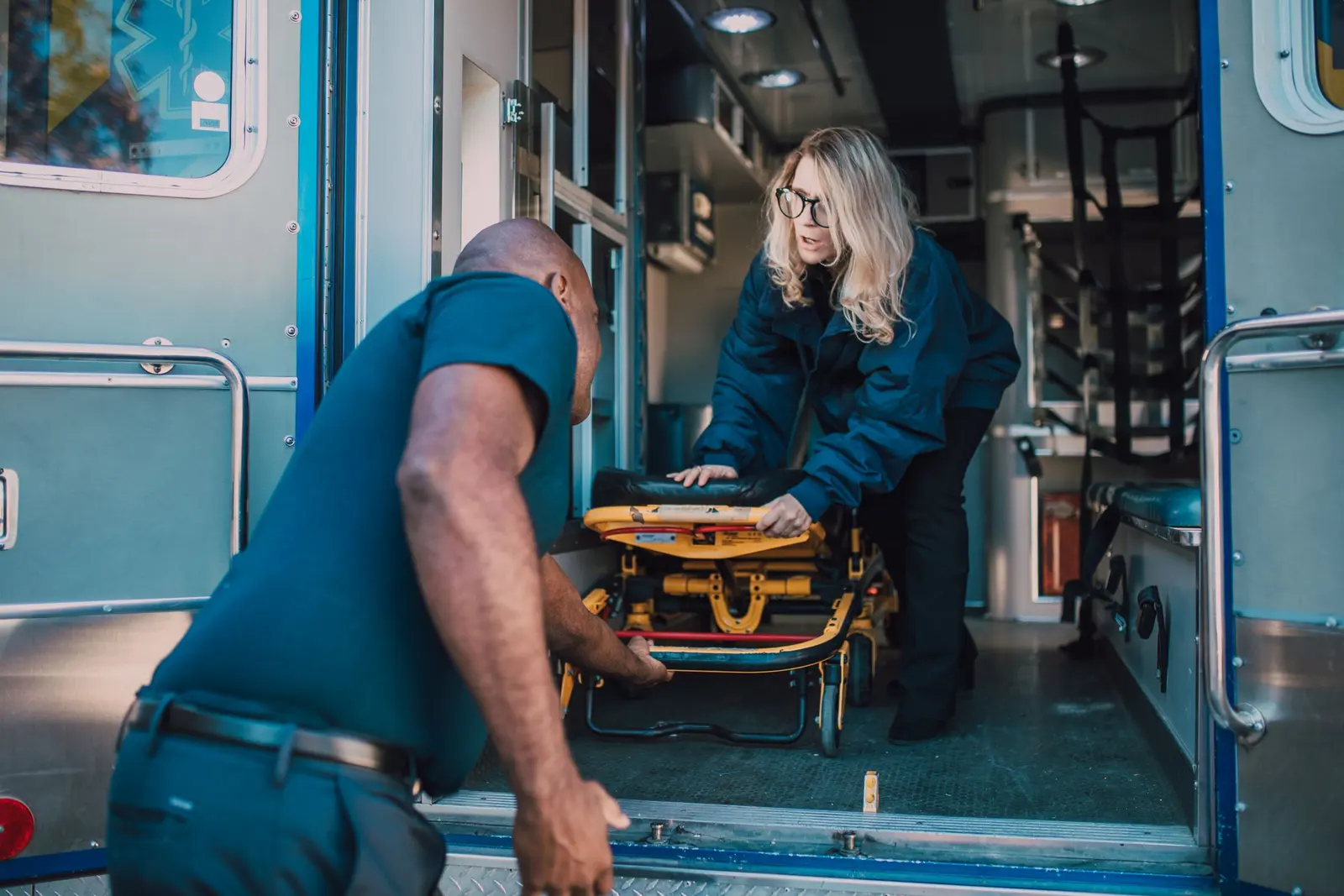 Due operatori caricano una barella su un mezzo di soccorso dal portellone posteriore