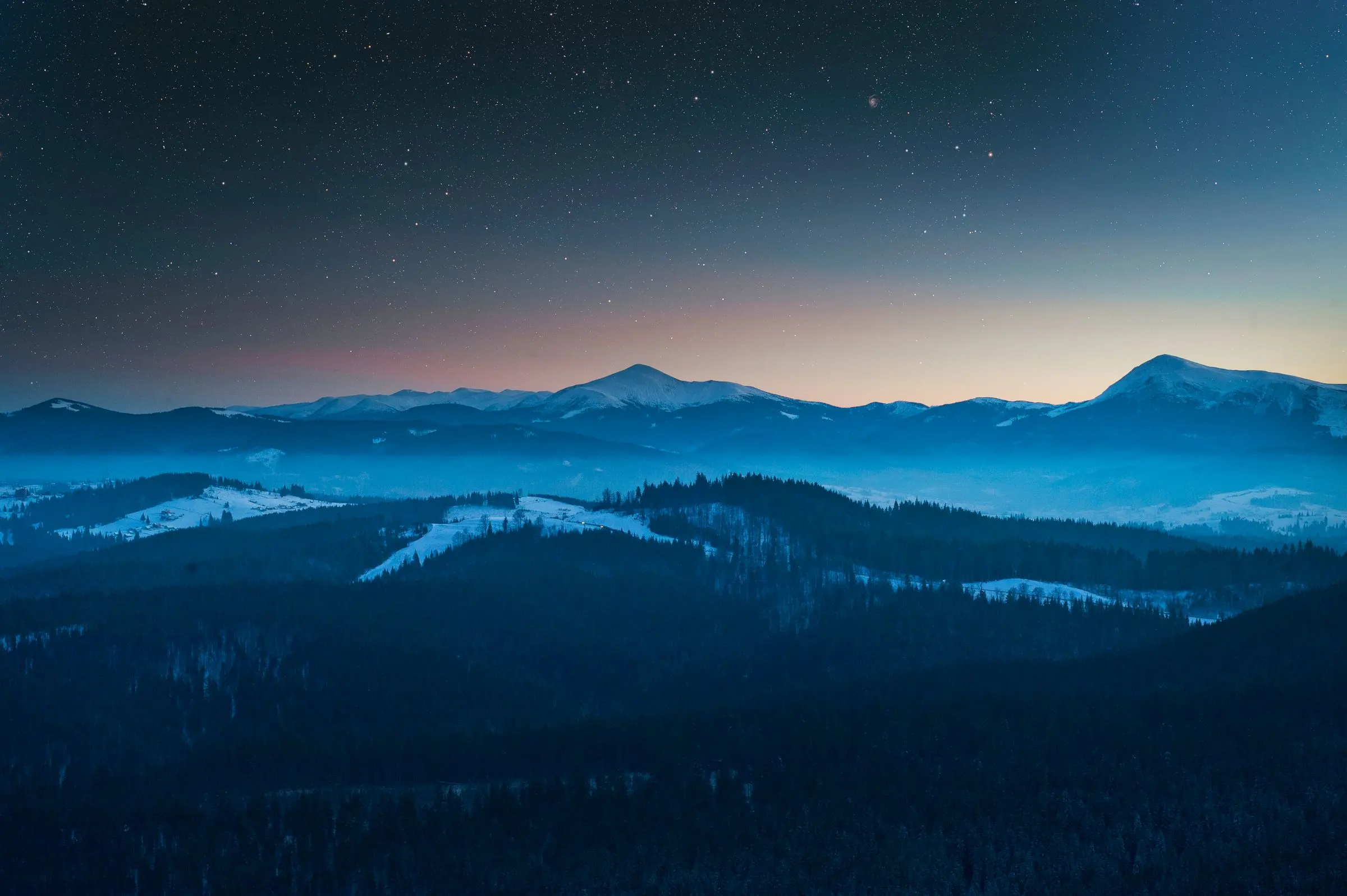 Montagne innevate all'ora blu, sotto un cielo con le prime stelle