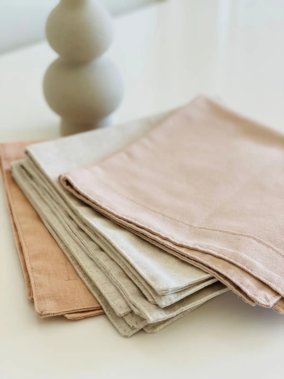 Tovaglioli di lino piegati, rosa cipria e color sabbia