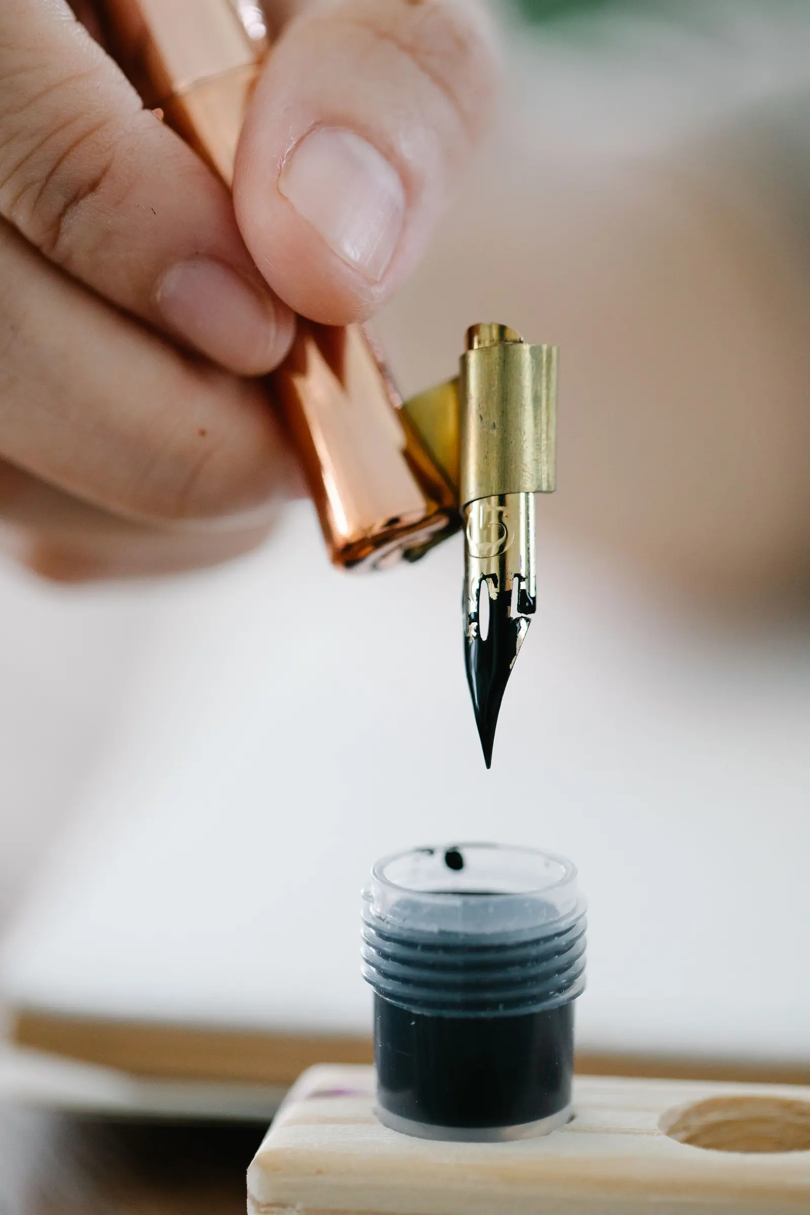 Un pennino da calligrafia d'ottone sospeso sopra un calamaio di inchiostro nero