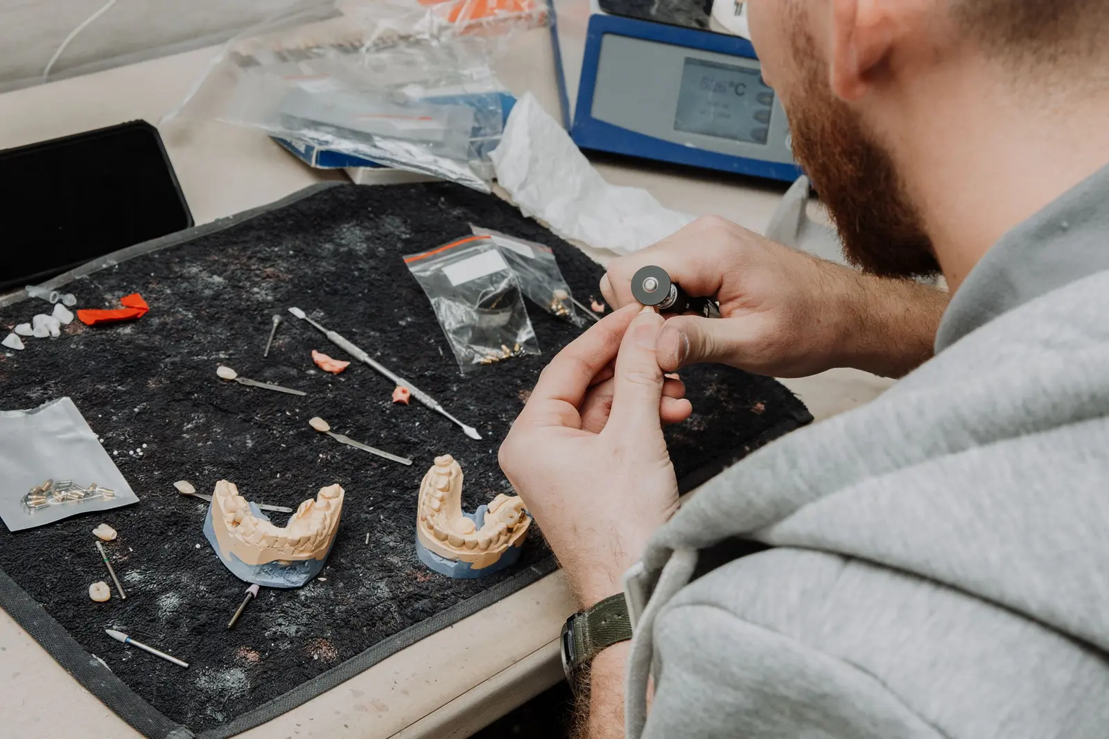 Odontotecnico al banco con modelli e strumenti, visto dall'alto