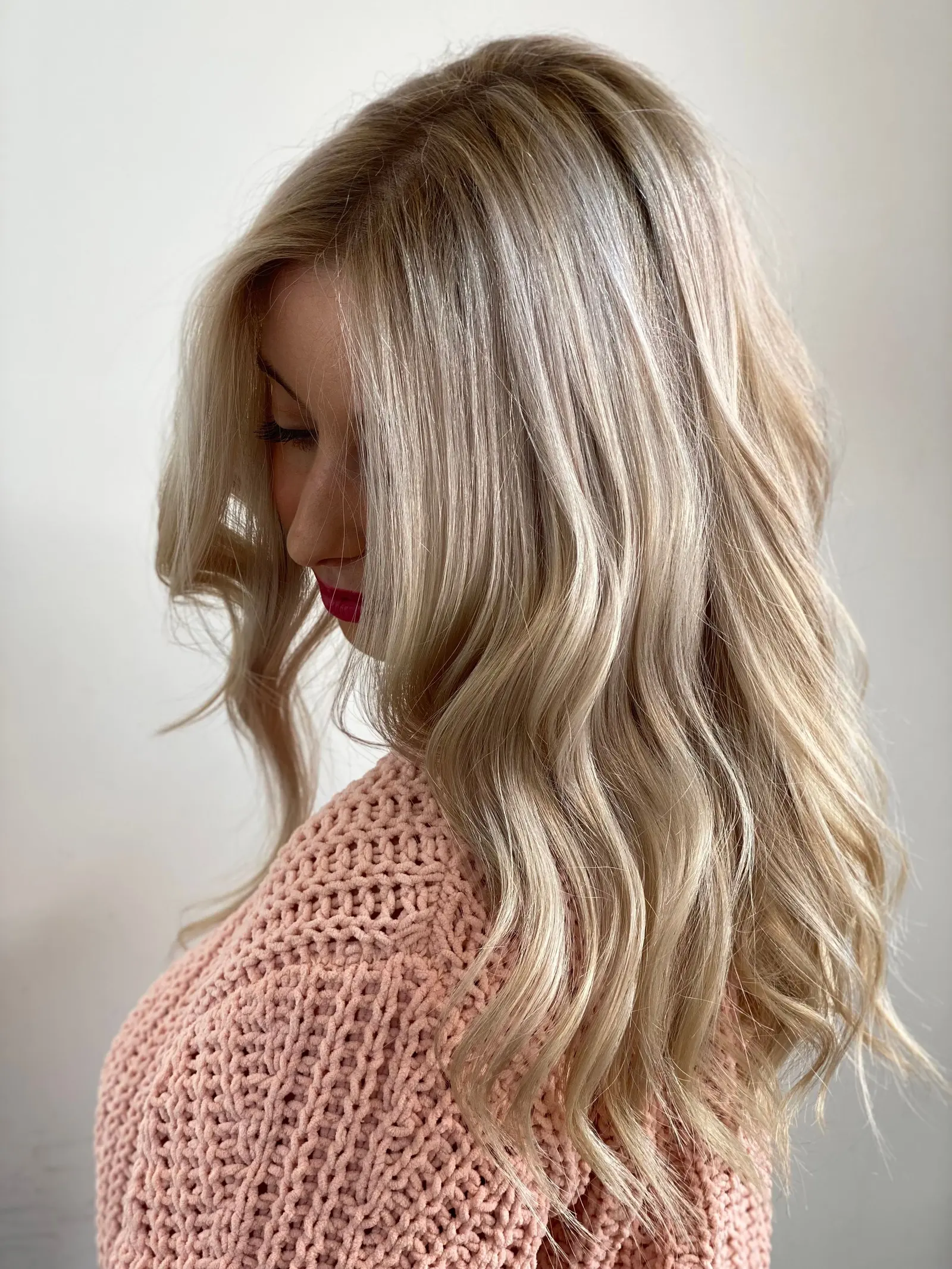 Capelli biondi luminosi e mossi, di profilo, su una maglia di lana