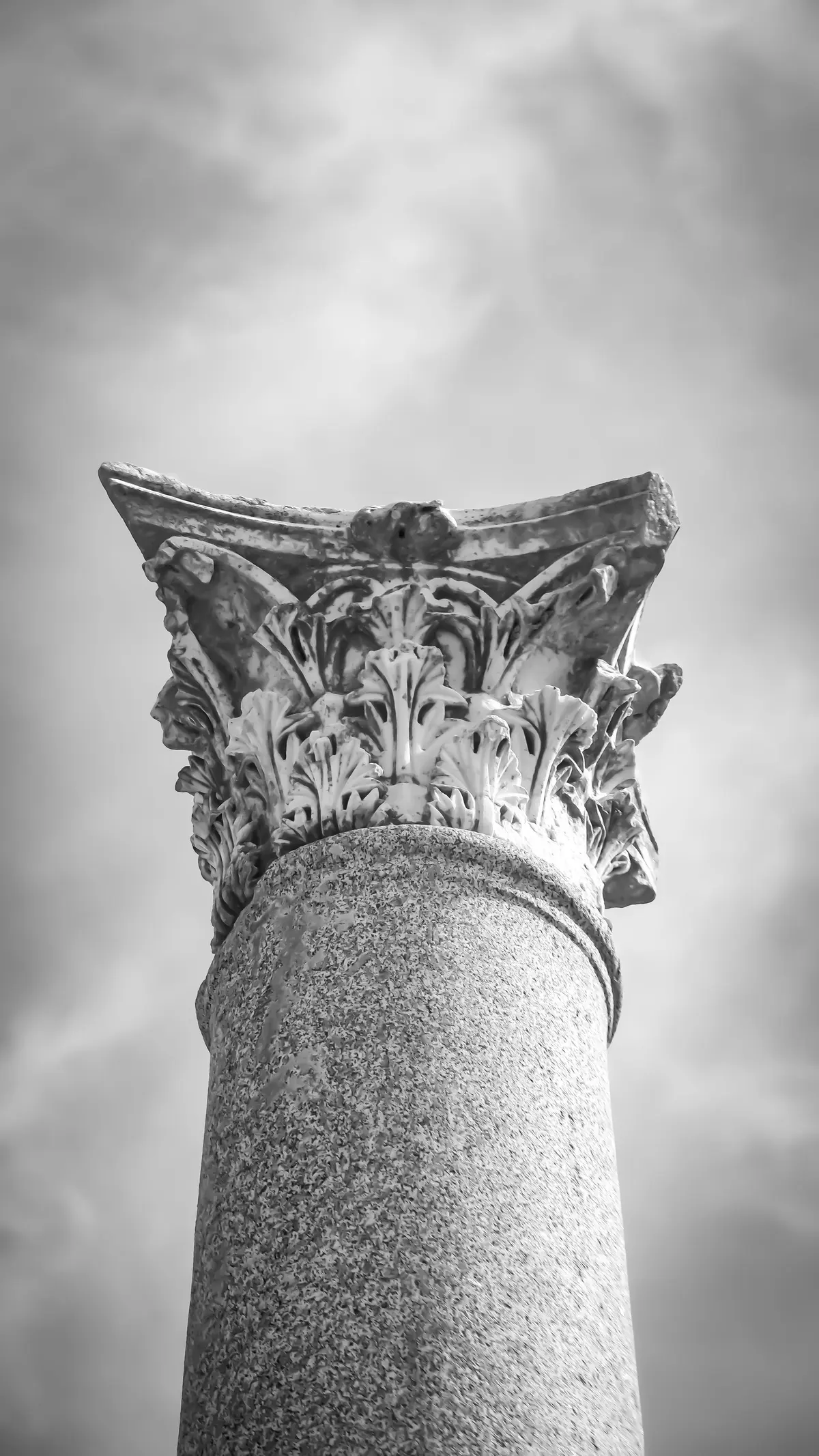 Capitello corinzio in pietra contro un cielo grigio