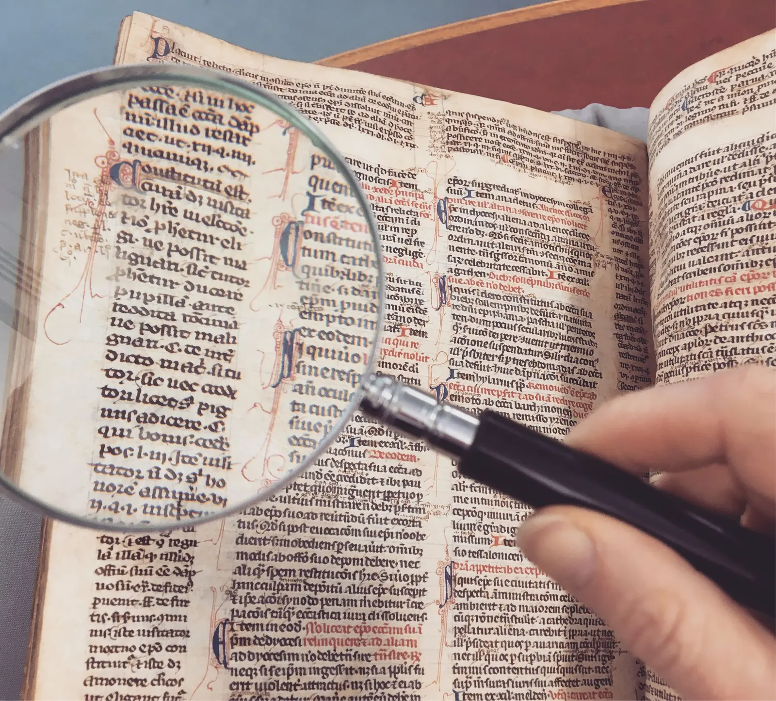 Lente d'ingrandimento su un codice giuridico medievale con le rubriche in rosso