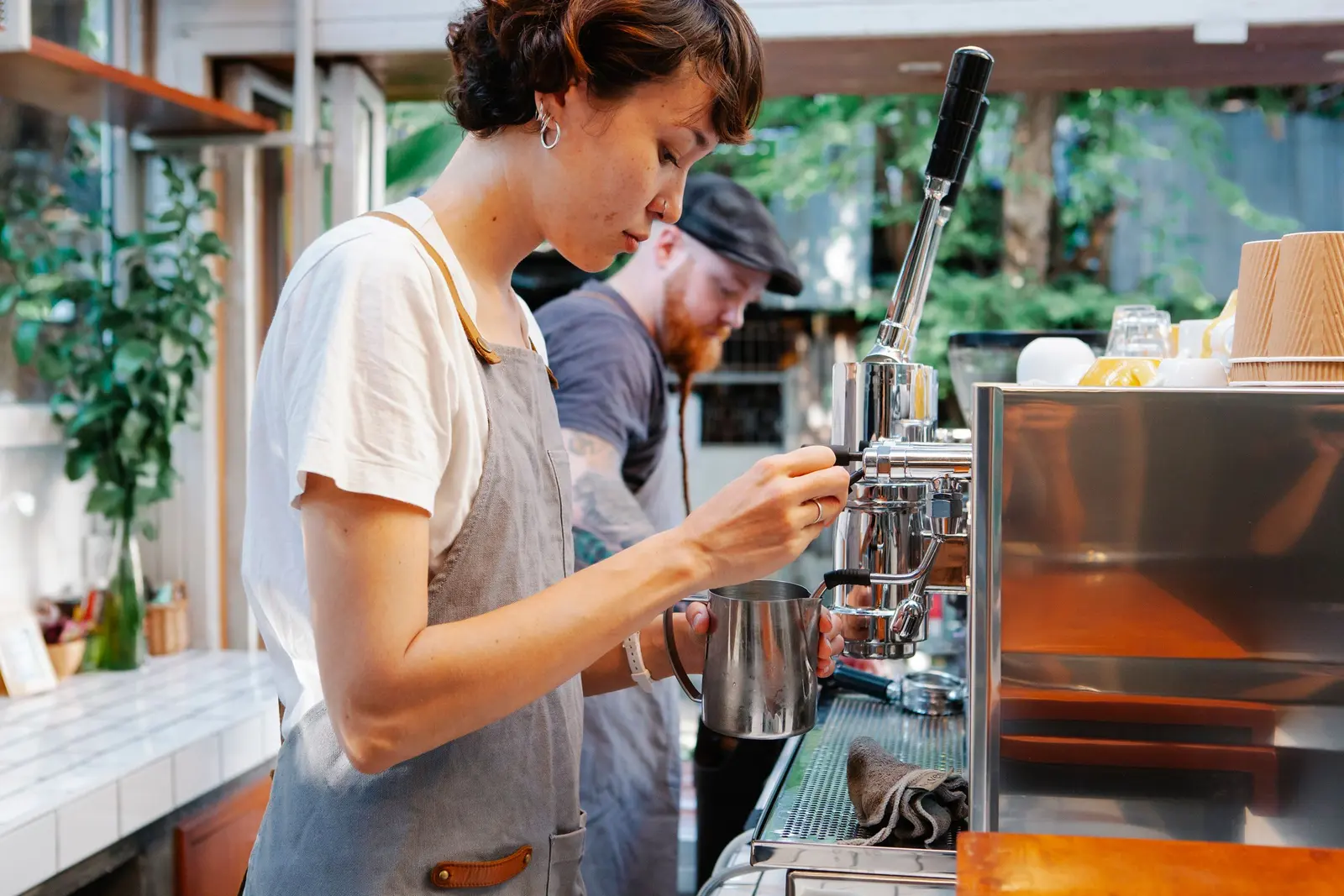 Una ragazza con il grembiule che prepara un caffè alla macchina di un bar