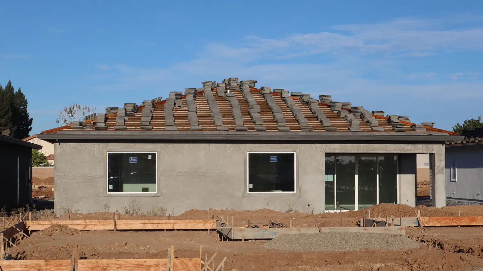 Una casa a un piano in costruzione, con il tetto in tegole già posato e i muri ancora grezzi
