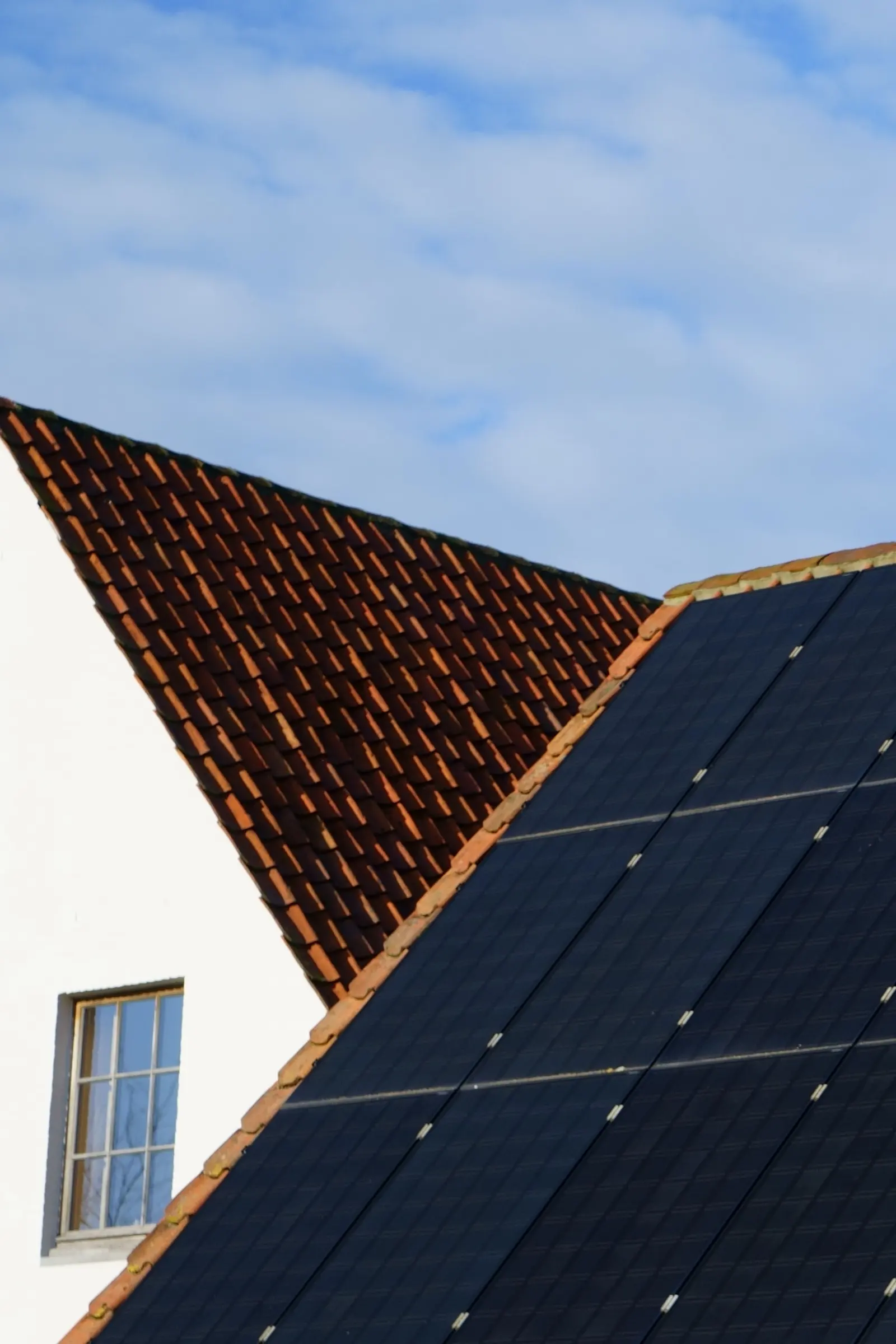 Pannelli fotovoltaici neri su un tetto in tegole, sotto il cielo azzurro