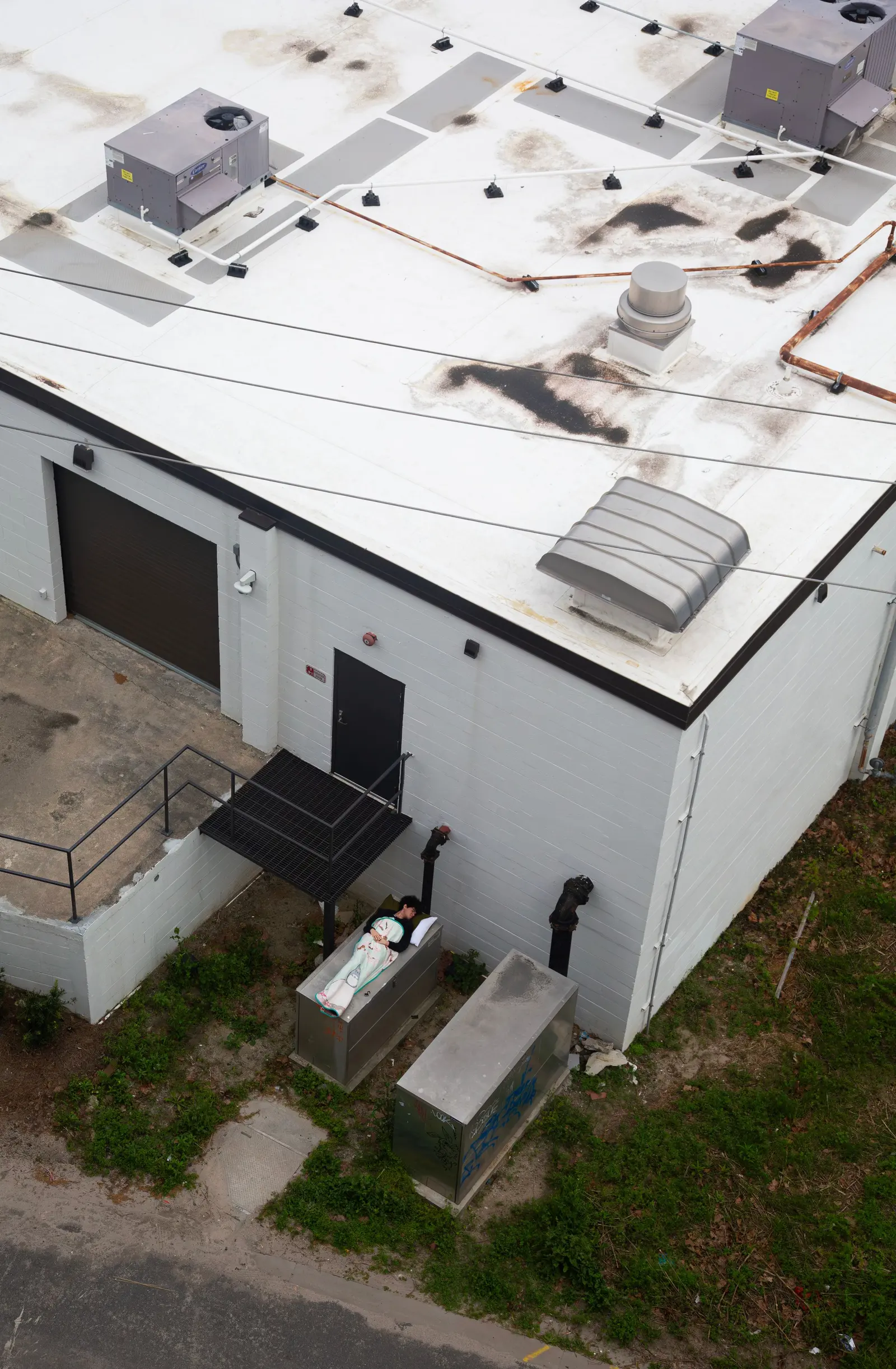 Tetto piano bianco visto dal drone, con macchine e aloni scuri attorno agli impianti
