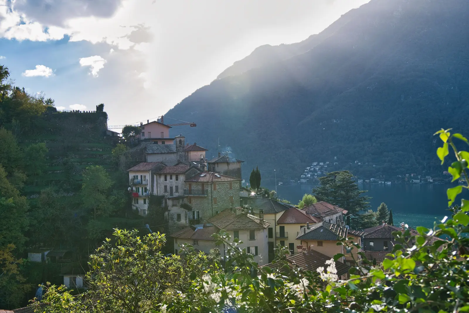 Un paese di case in pietra sul pendio sopra il lago, in controluce