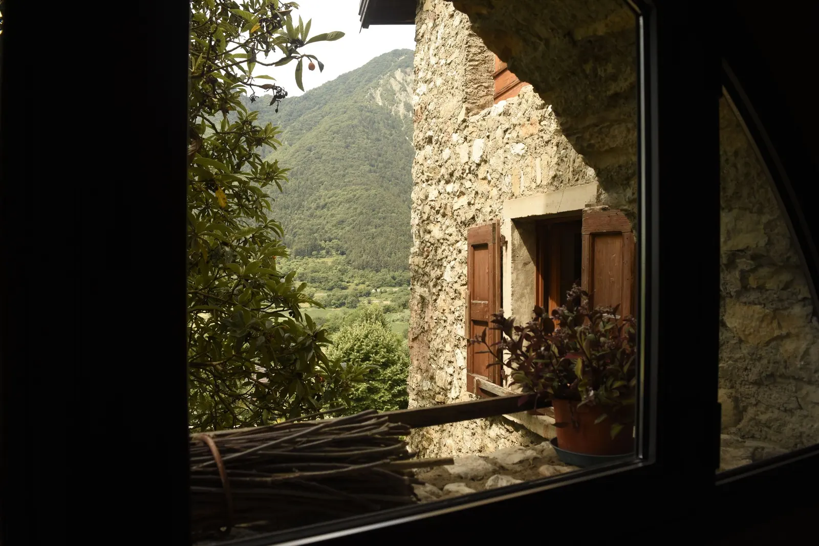 Finestra di una casa in pietra aperta sulla valle verde