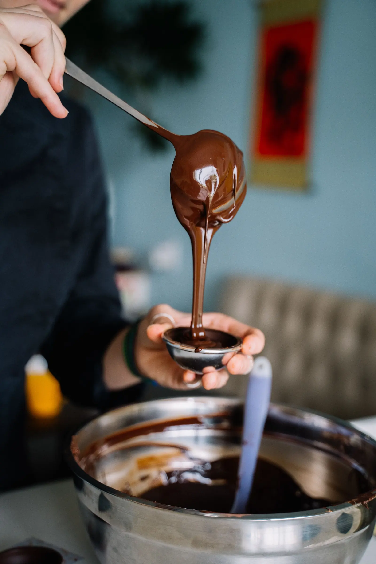 Cioccolato fuso versato da un mestolo in uno stampo a semisfera