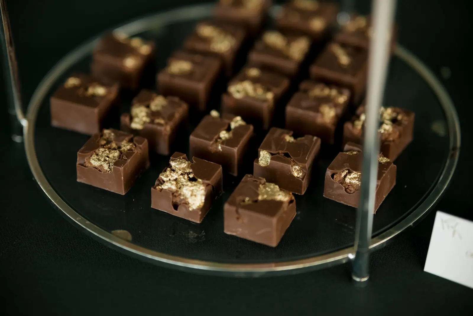Praline quadrate con una scaglia di foglia d'oro, su un vassoio di vetro