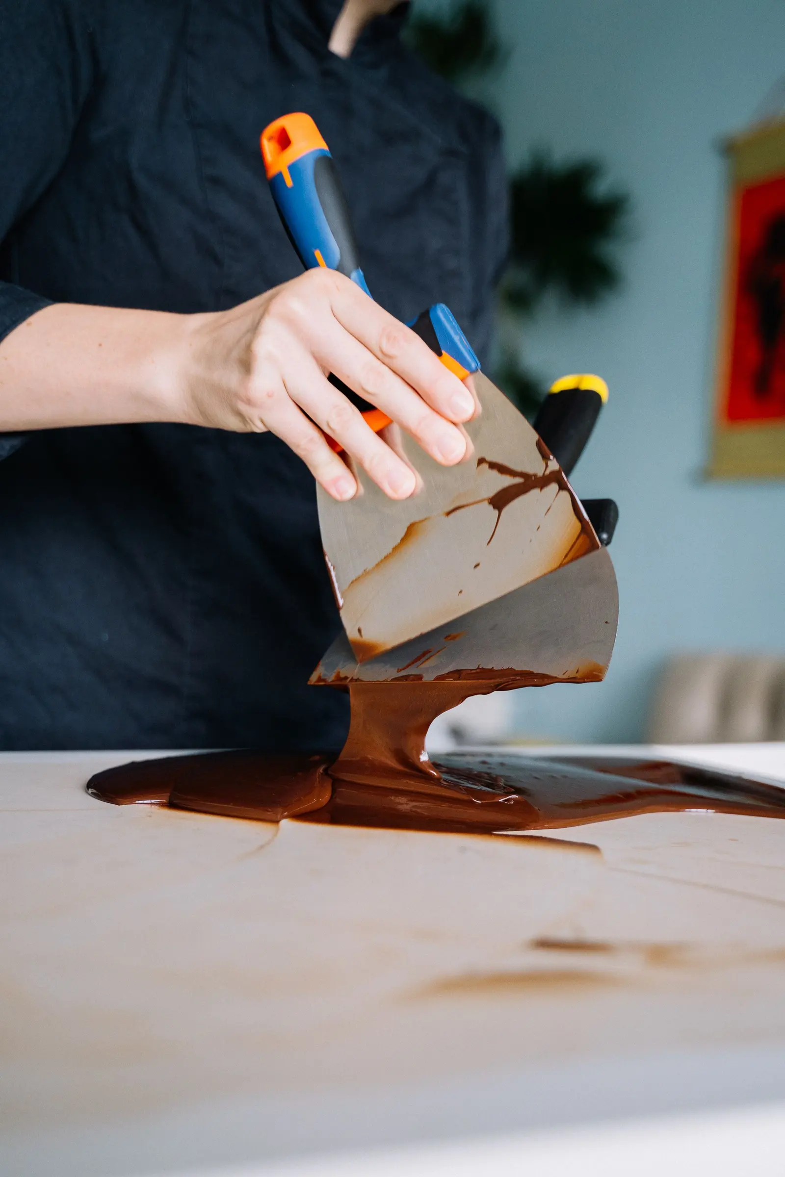 Mani che stendono il cioccolato fuso sul marmo con una spatola