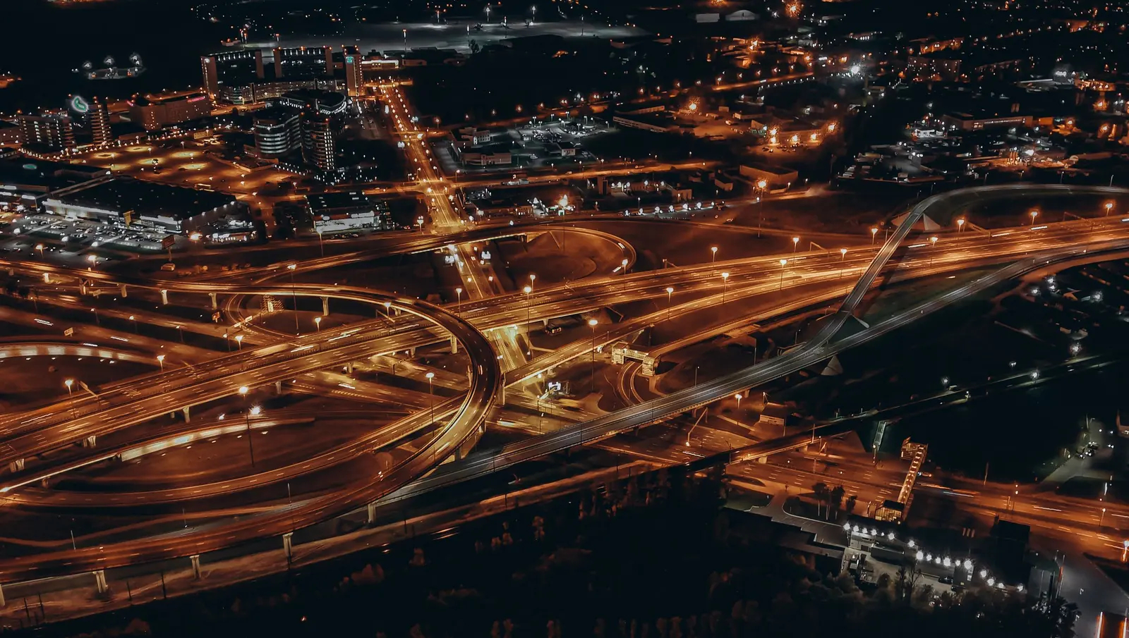 Svincoli autostradali illuminati di arancio nella notte, visti dall'alto