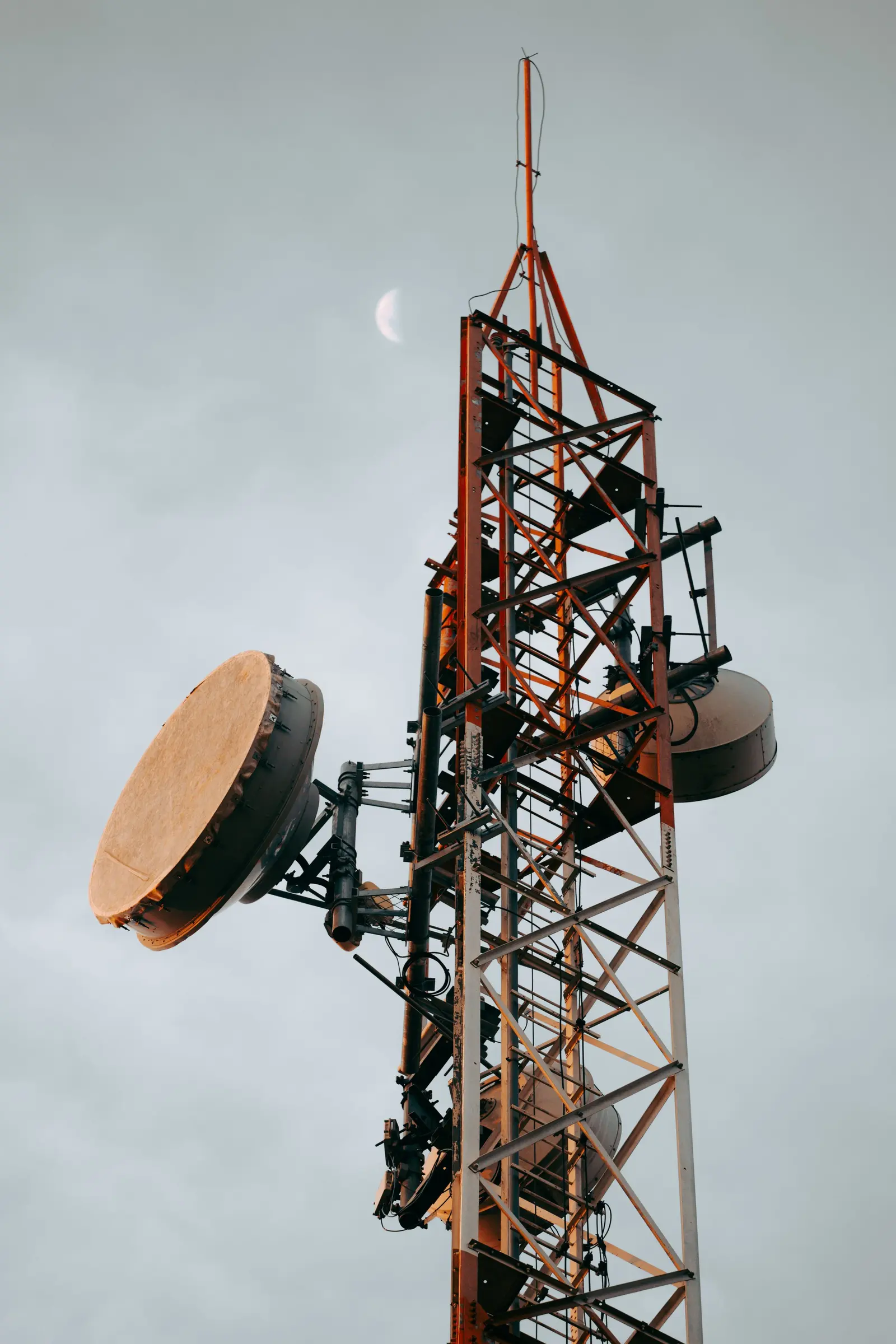 Una parabola per ponte radio montata su un traliccio d'acciaio, contro un cielo grigio