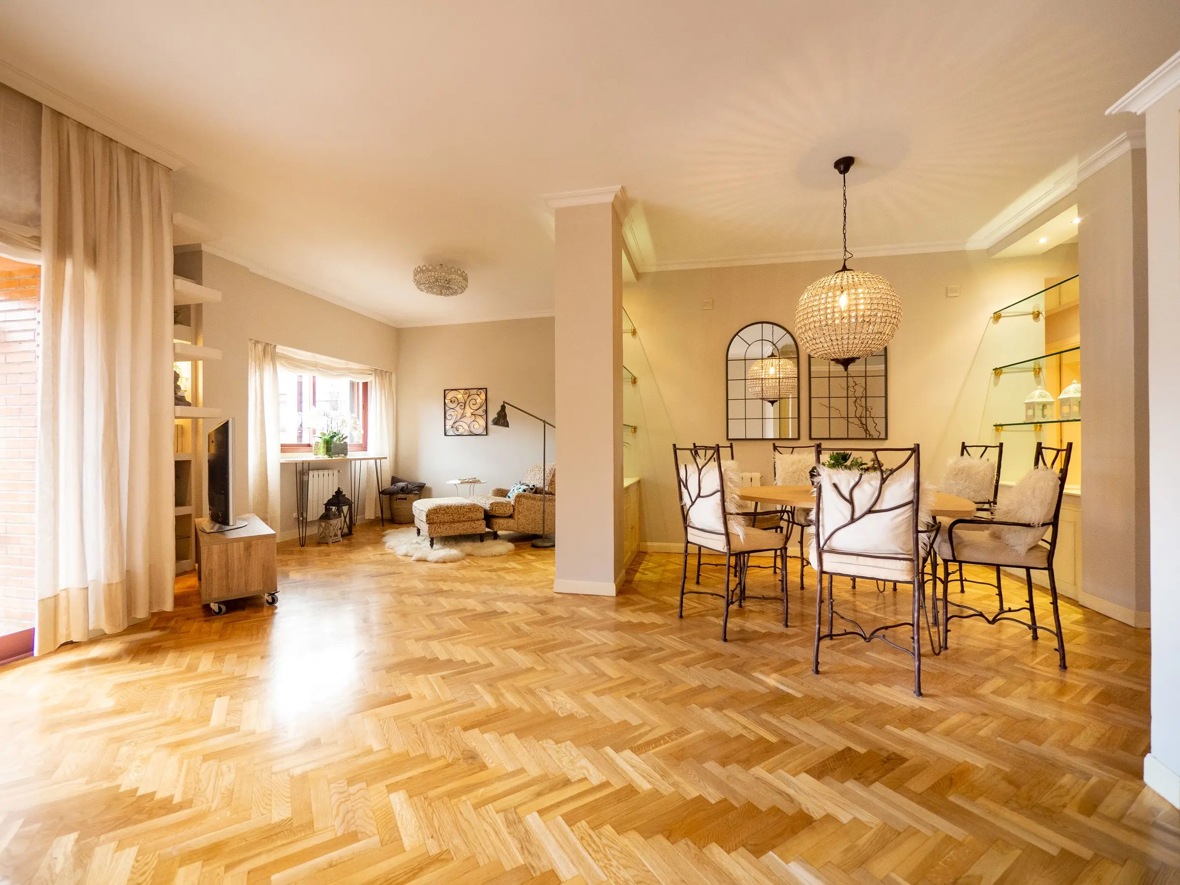 Dopo: soggiorno e zona pranzo luminosi con parquet a spina di pesce, tende chiare e una lampada in vimini