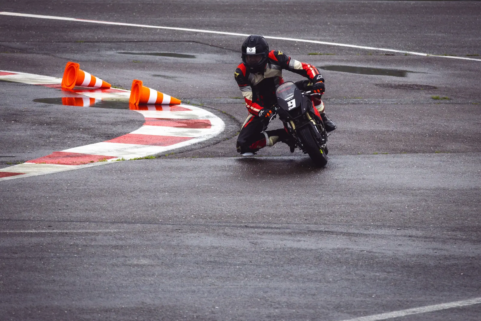 Pilota in moto in piega tra due birilli arancioni durante un esercizio