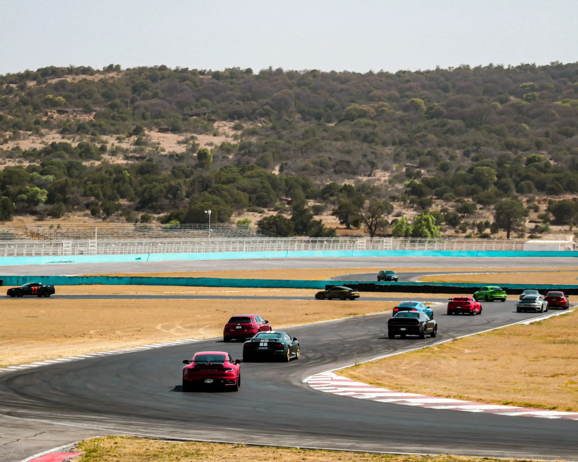 Una fila di auto in un curvone durante un track day, colline sullo sfondo