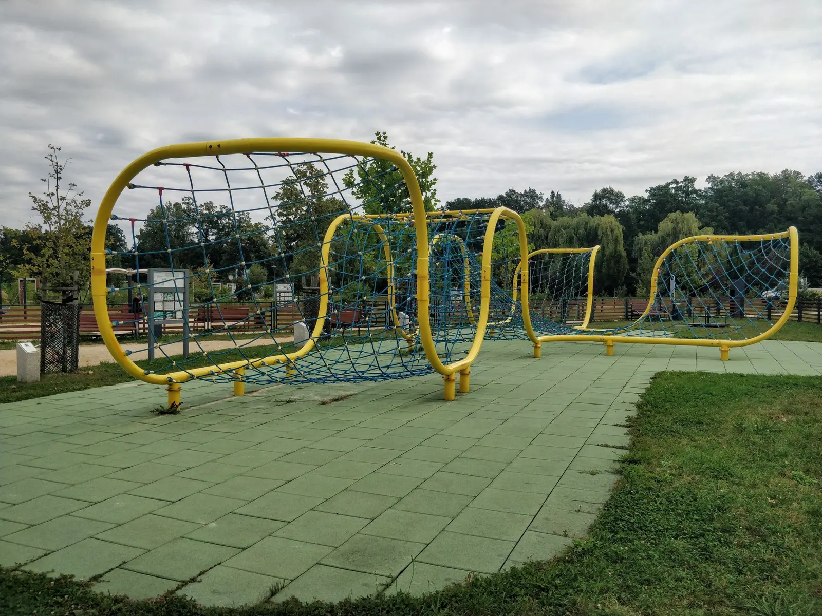 Percorso di archi gialli con reti di funi, su piastre antitrauma verdi in un parco