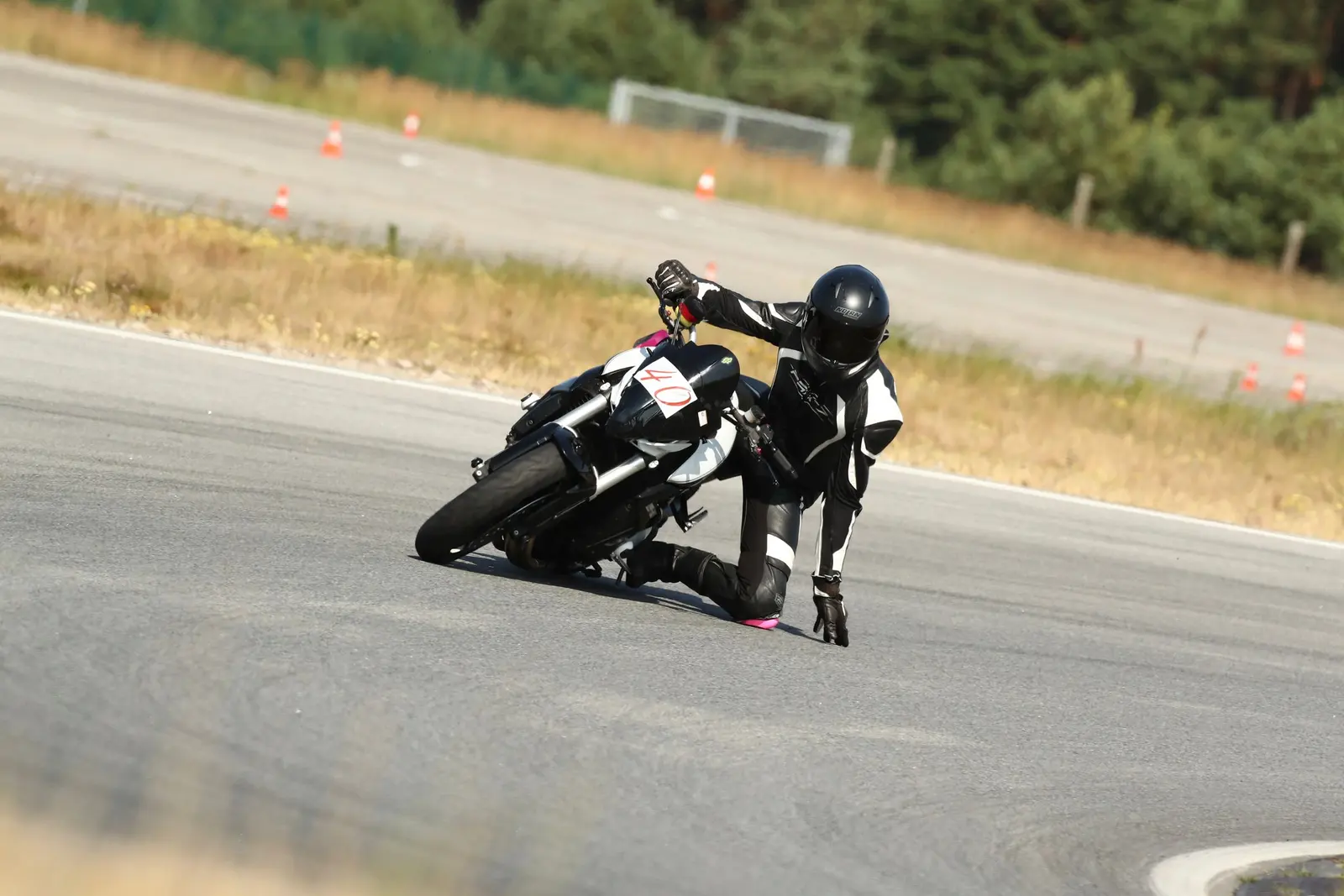 Pilota in tuta bianca e nera con il ginocchio a terra in curva