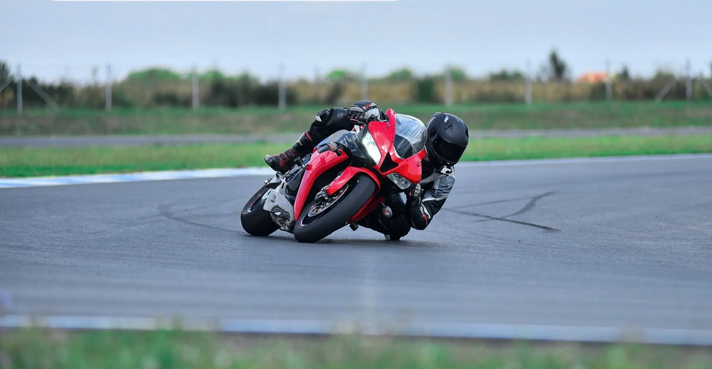 Una supersportiva rossa in piega su un curvone, pilota in tuta nera