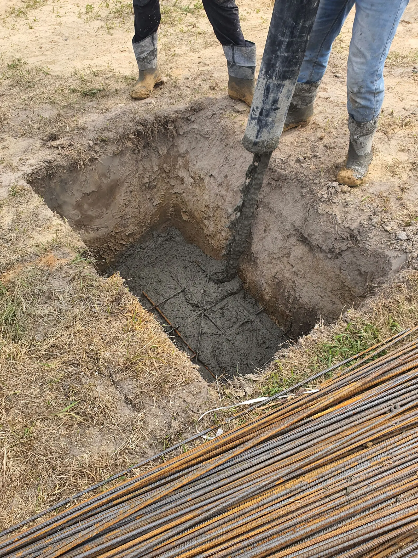 Il calcestruzzo versato in uno scavo di fondazione, con i tondini di ferro a terra