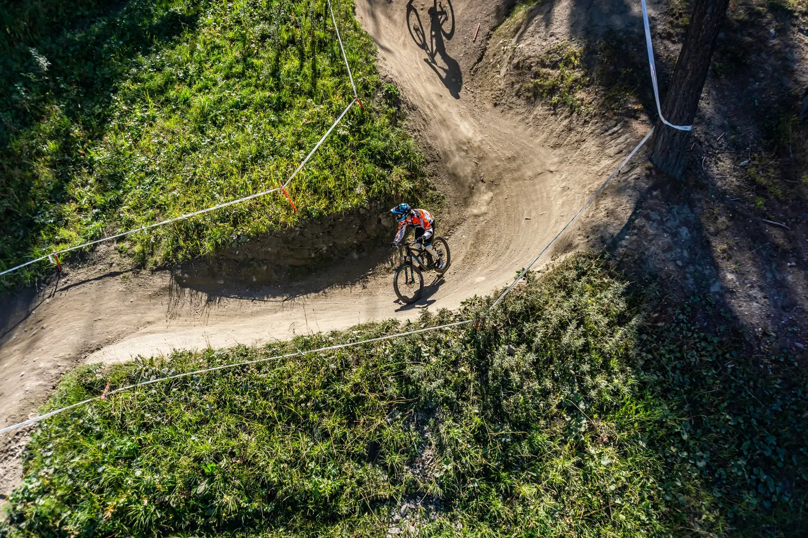 Vista dall'alto di una pista con curve paraboliche nel bosco, un rider in curva