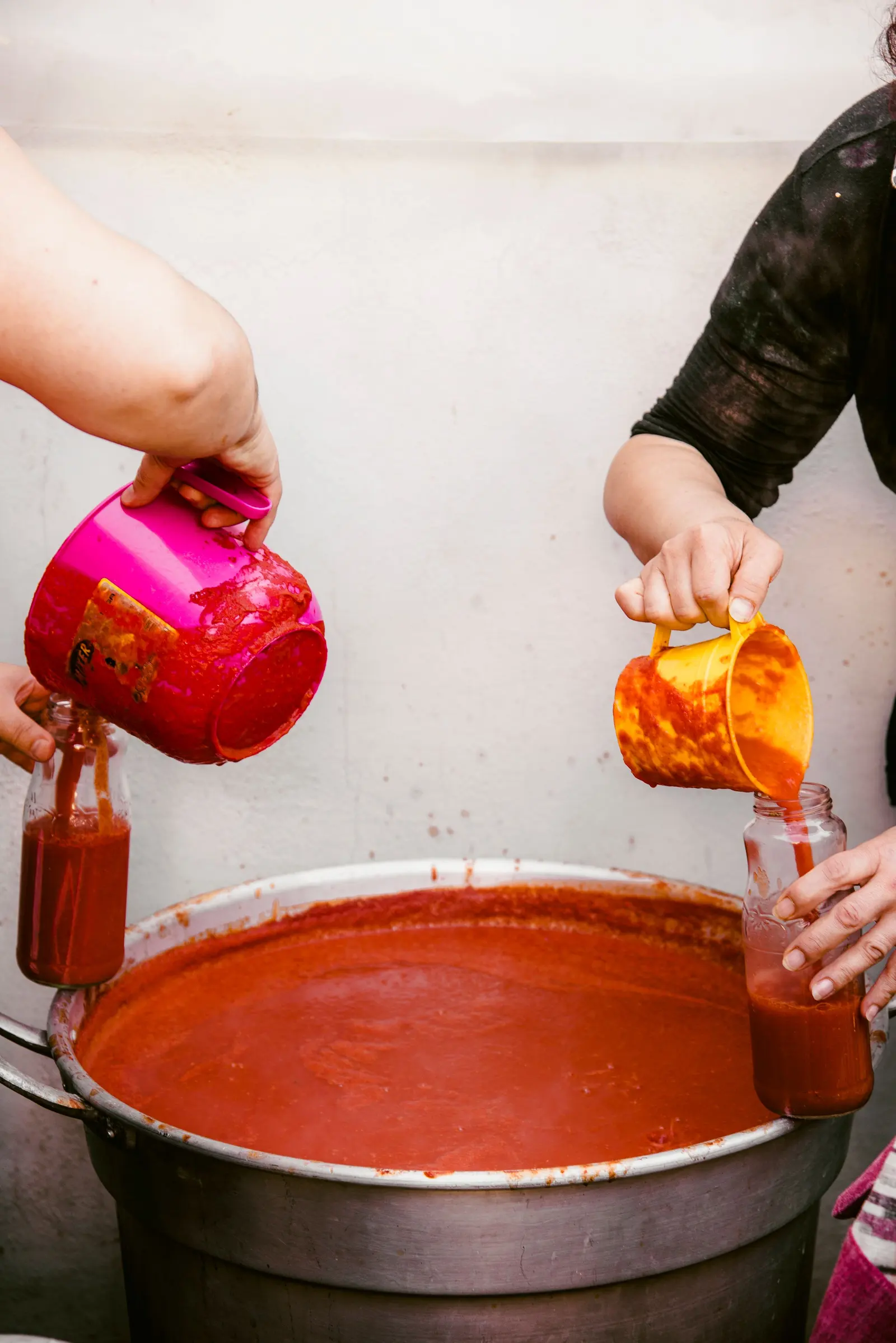 Passata di pomodoro calda versata dalla pentola nei vasi