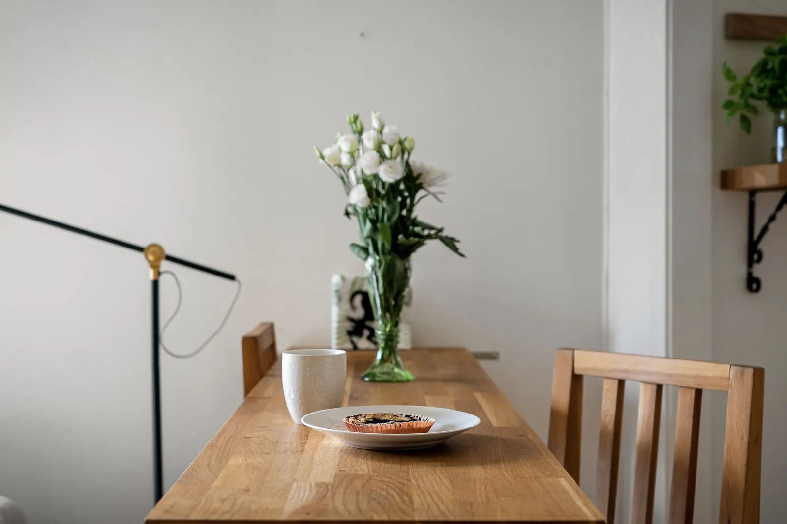 Il piano di un tavolo in legno con un vaso di fiori bianchi e una tazza