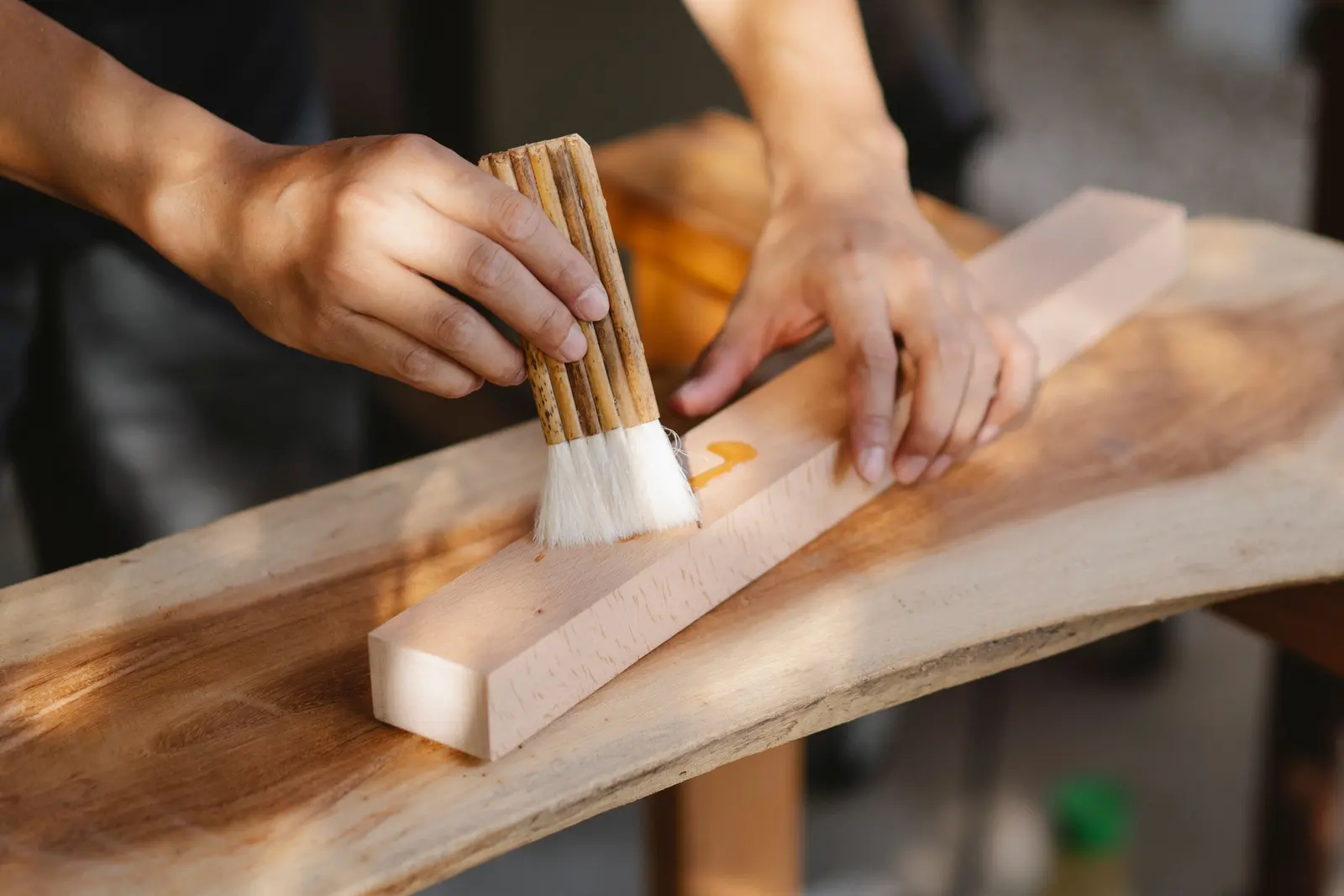 Un pennello stende l'olio su un listello di legno appoggiato su una tavola