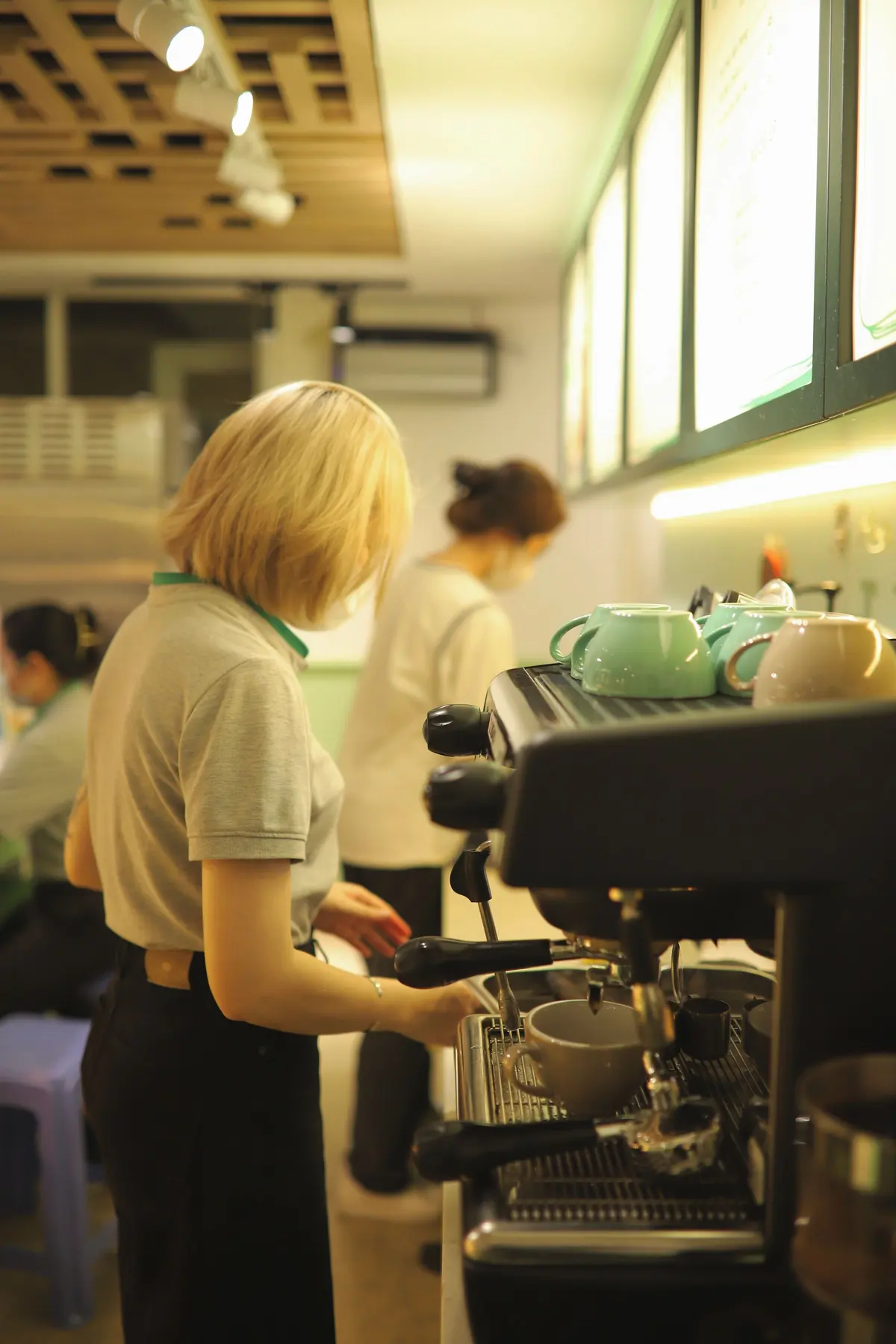 Due bariste dietro il bancone, una alla macchina del caffè