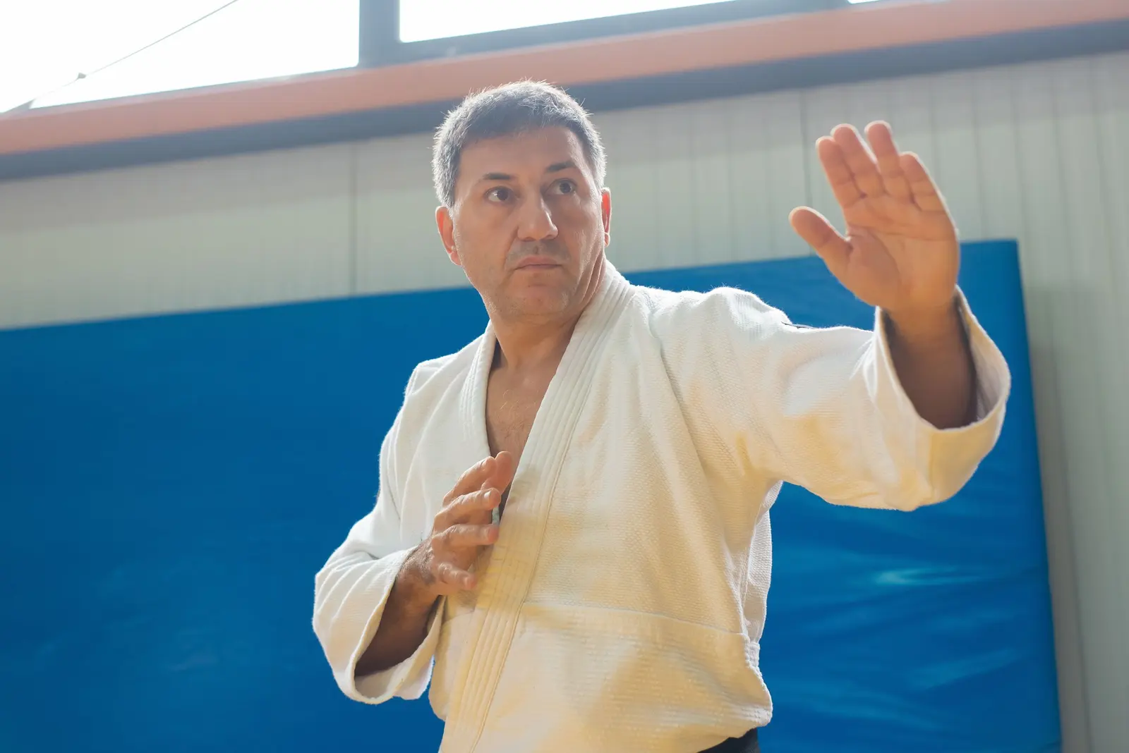 Uomo maturo in judogi in posizione di guardia a mani aperte