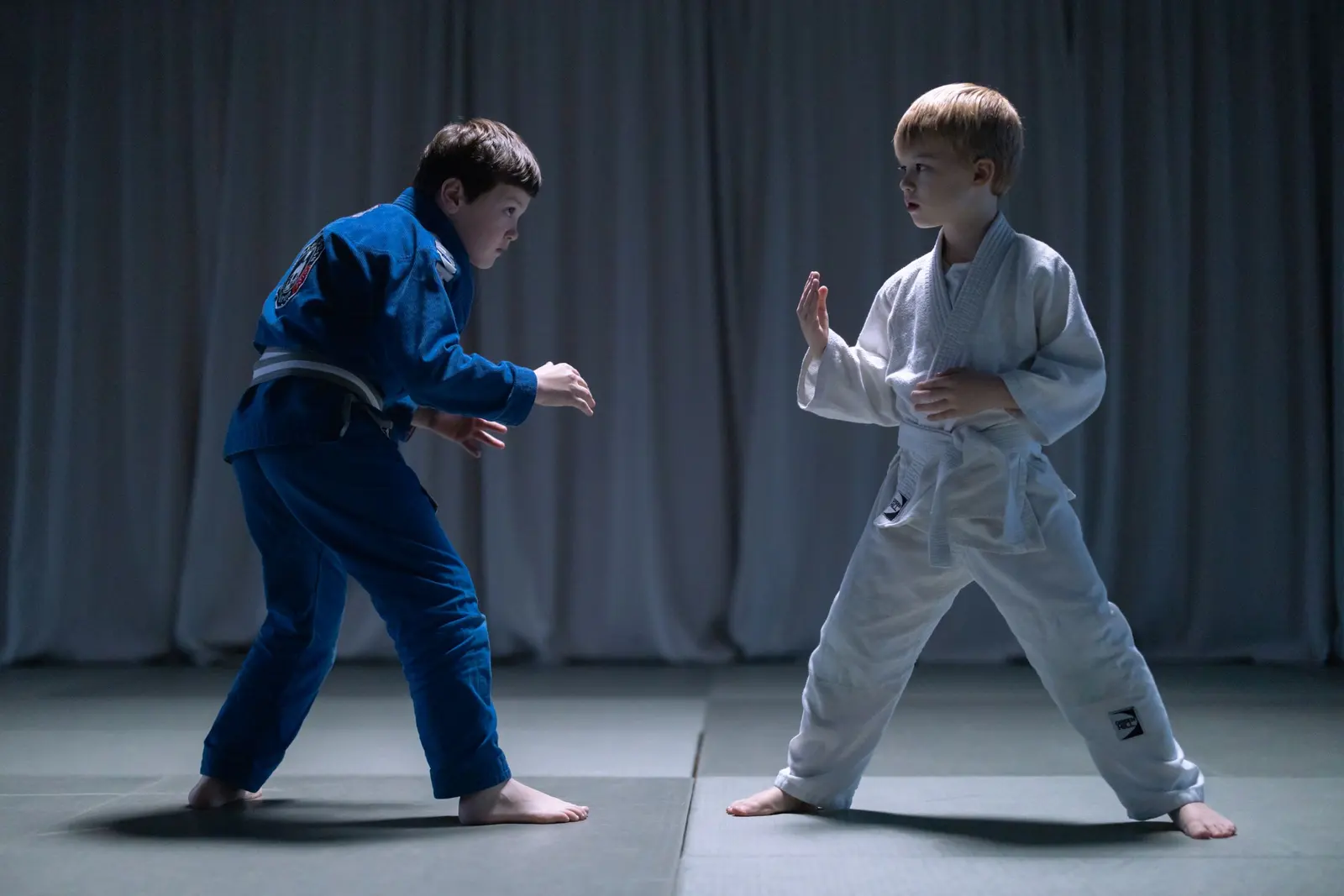 Due ragazzi in judogi blu e bianco si studiano prima della presa
