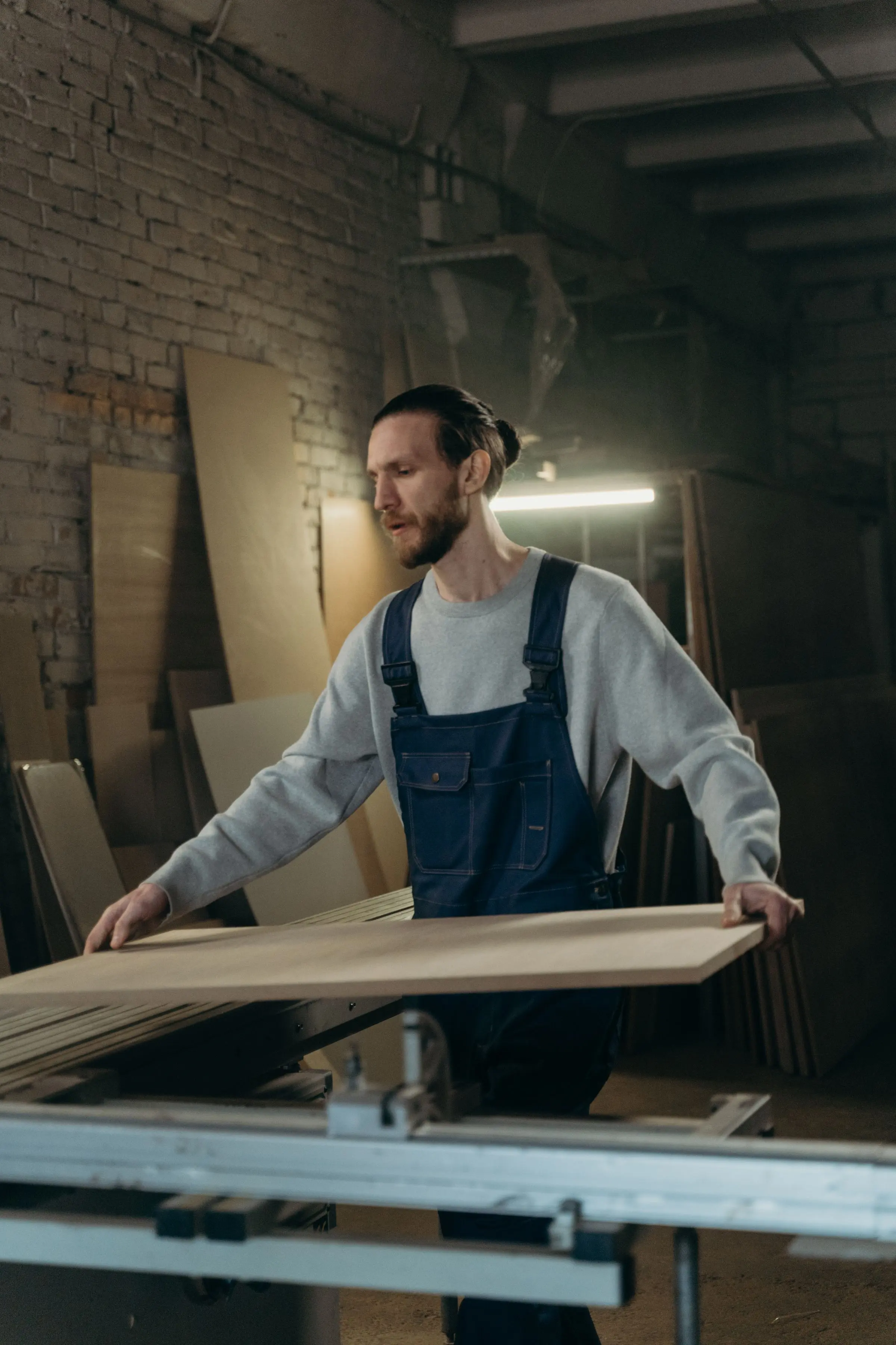 Falegname che porta un pannello di legno sul banco della sezionatrice