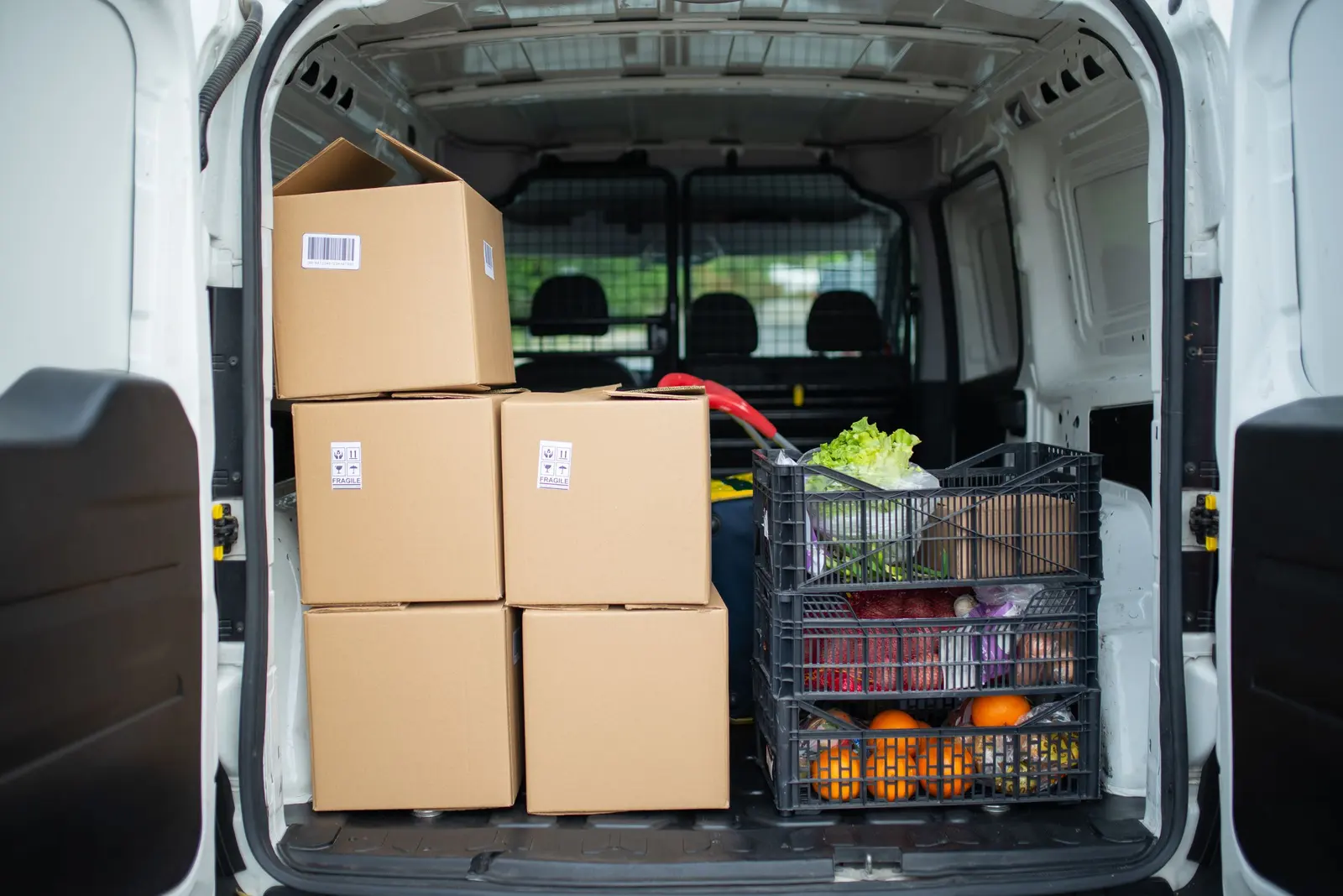 Vano di carico aperto da dietro con scatoloni e una cassetta di frutta e verdura