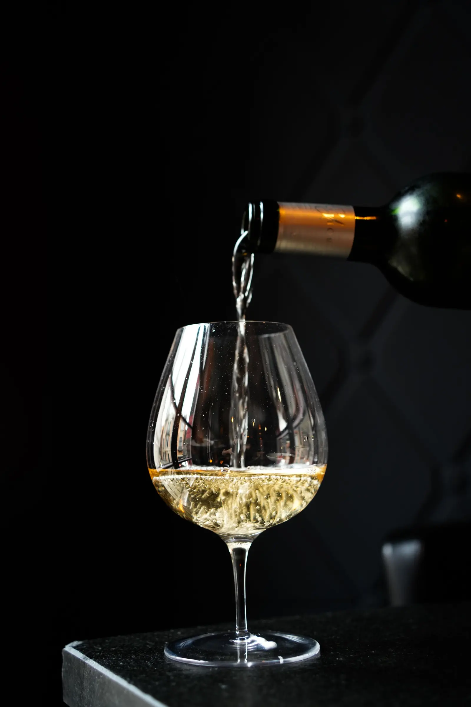Vino bianco versato in un calice, su fondo nero