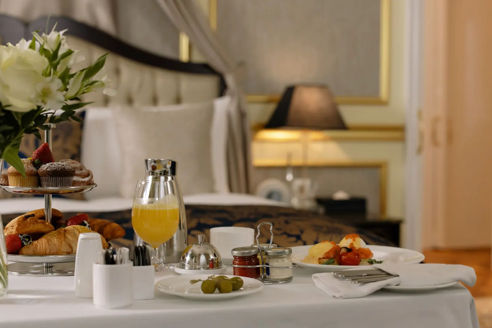 Colazione servita in camera: brioche, spremuta d'arancia, frutta e caffè su una tovaglia bianca