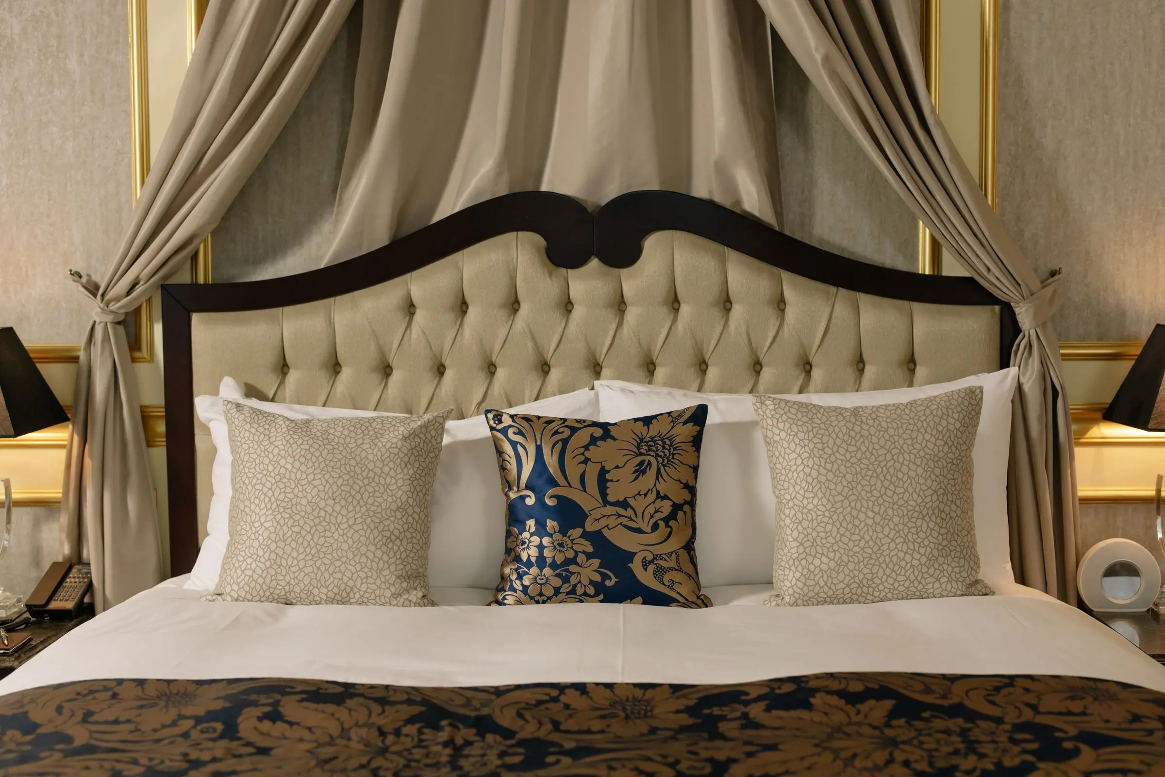 Letto a baldacchino con testiera imbottita e cuscini blu e oro nella Suite affrescata